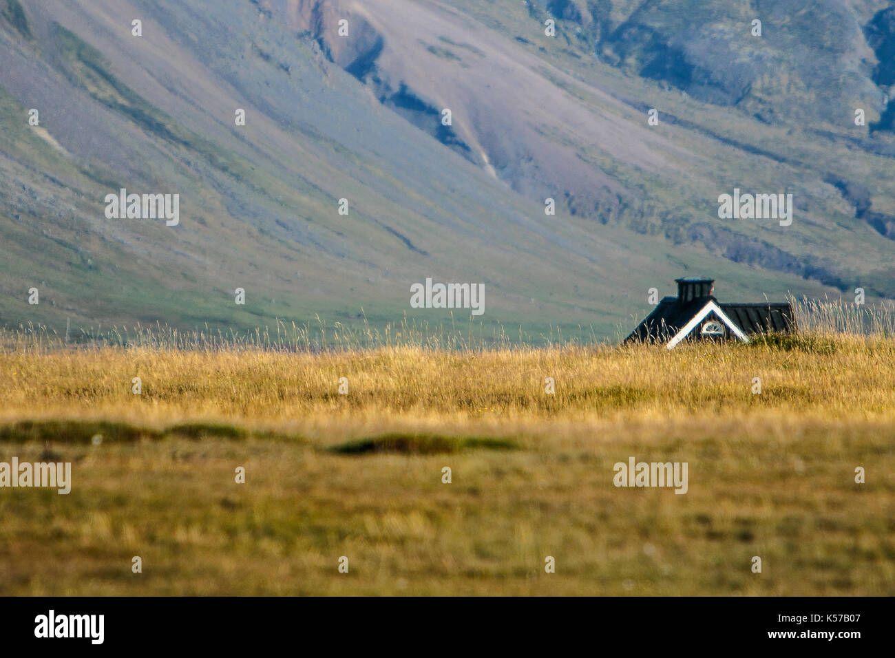 Paysage montagneux avec une maison rurale visible au-dessus du champ en premier plan. Banque D'Images