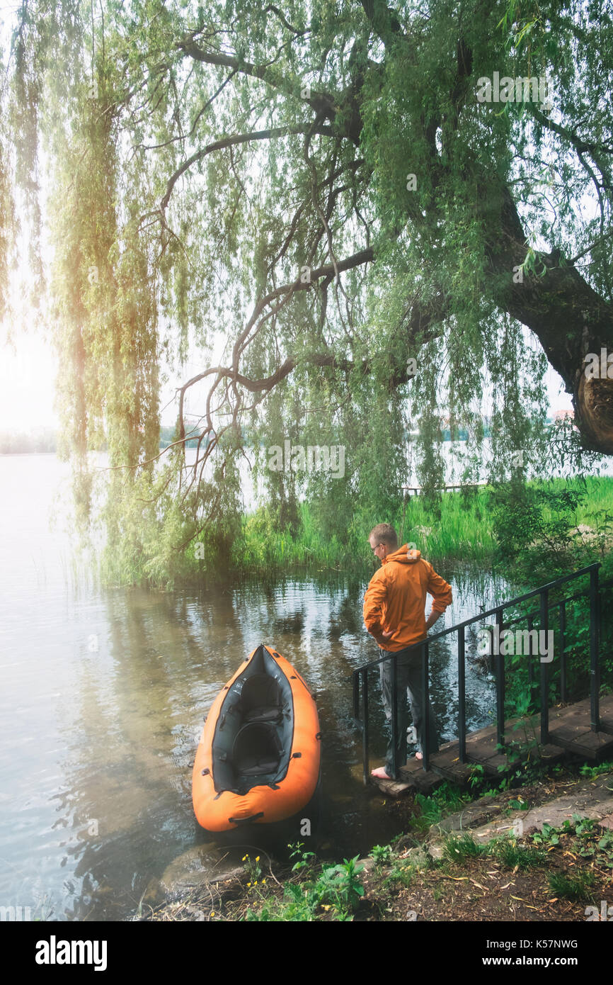 Dans l'homme veste orange près d'orange en kayak. matin ensoleillé sur le magnifique lac de l'heure d'été. Banque D'Images