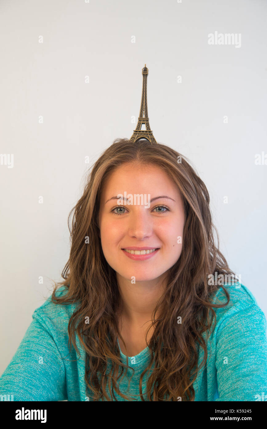 Jeune femme souriante avec une reproduction grandeur nature de la Tour Eiffel sur la tête. Banque D'Images