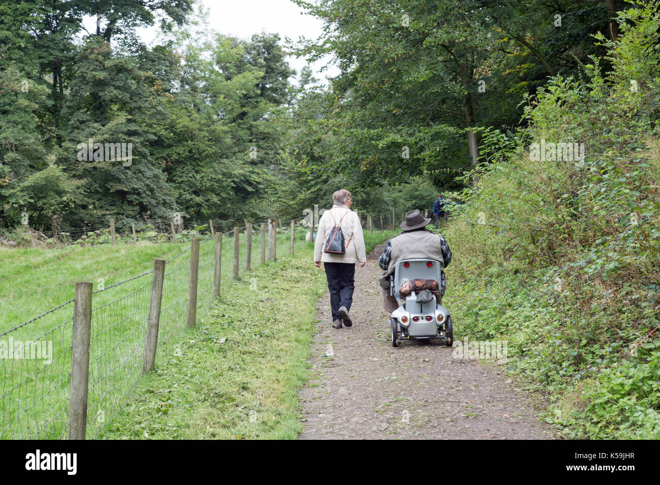 Septembre 2017, un couple, une mobilité et en utilisant une aide à la mobilité voyager sur un chemin dans la campagne. Banque D'Images