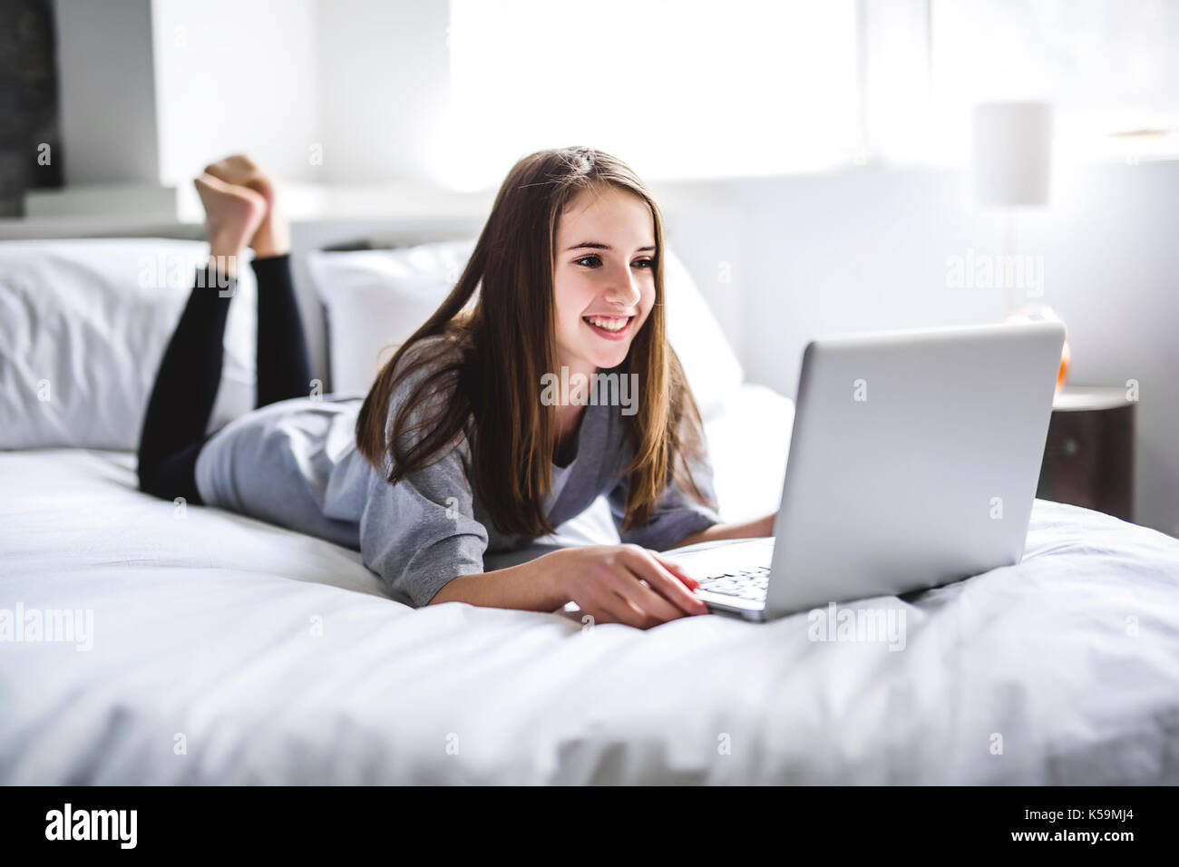 A young girl lying on bed using a laptop Banque D'Images