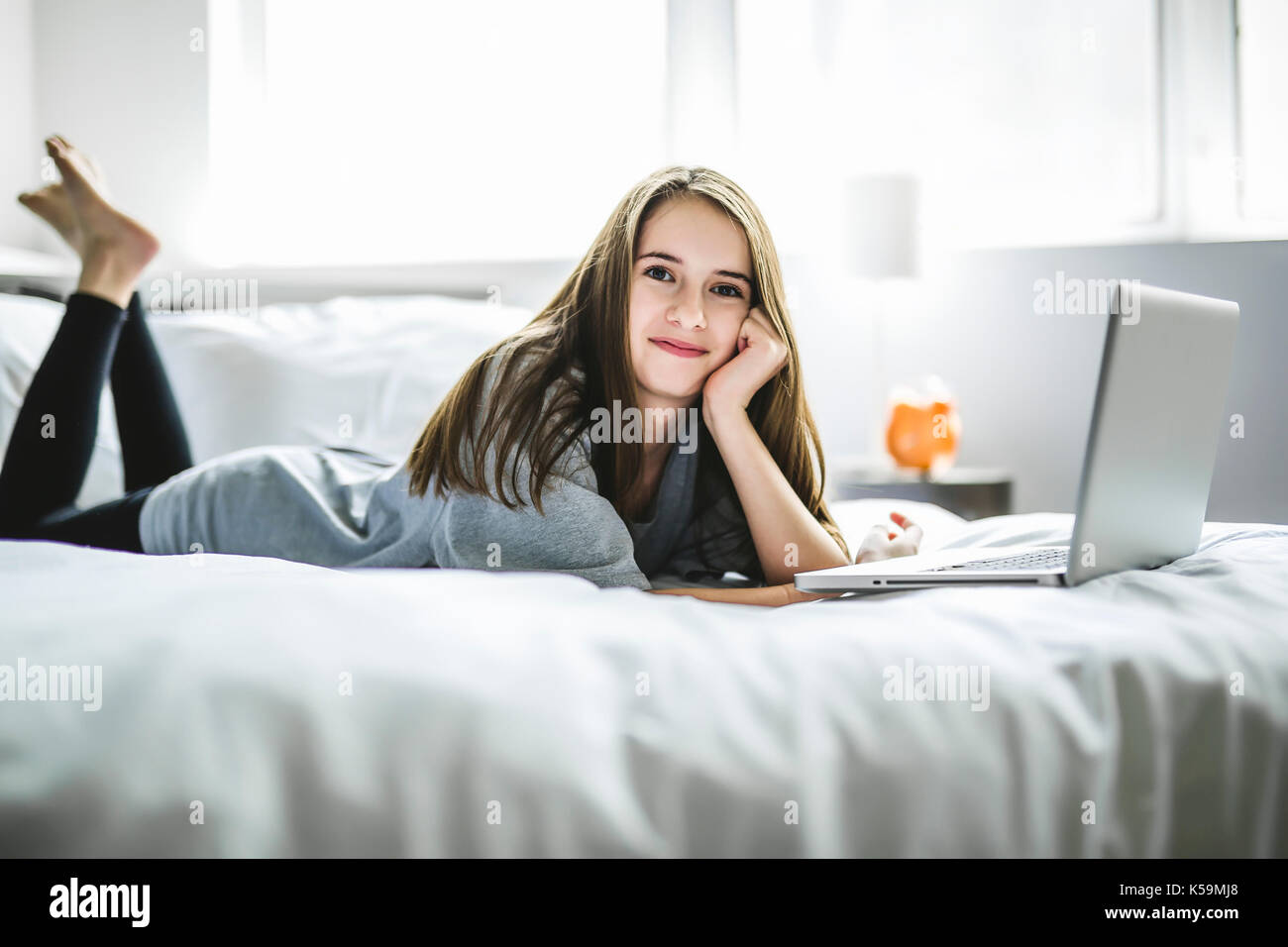 Teenage girl lying on bed using a laptop Banque D'Images