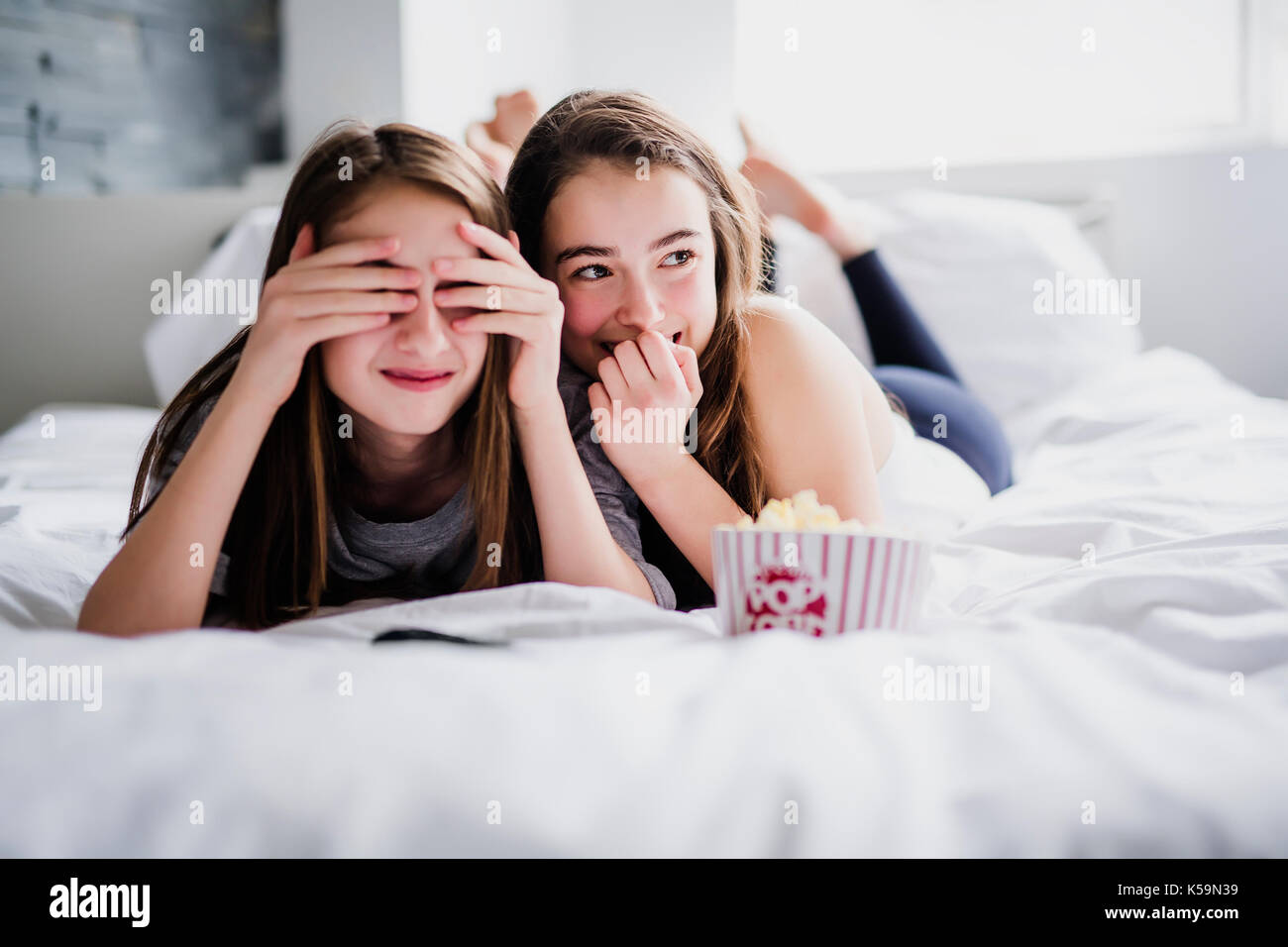 Teenage Girls eating popcorn et regarder des films d'horreur à la télé à la maison Banque D'Images