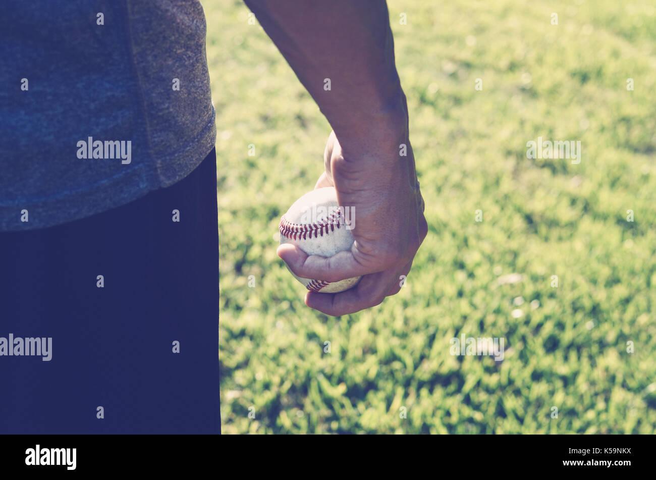 Joueur de baseball avec ballon en main pendant le coucher du soleil naturel, idéal pour les sports américains graphique. Banque D'Images
