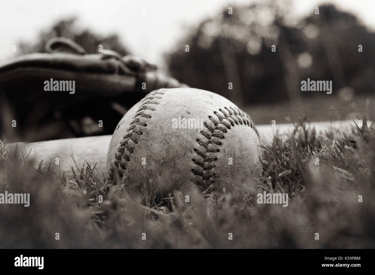 Old vintage baseball sur l'herbe après le jeu avec un gant et bat en arrière-plan. Banque D'Images