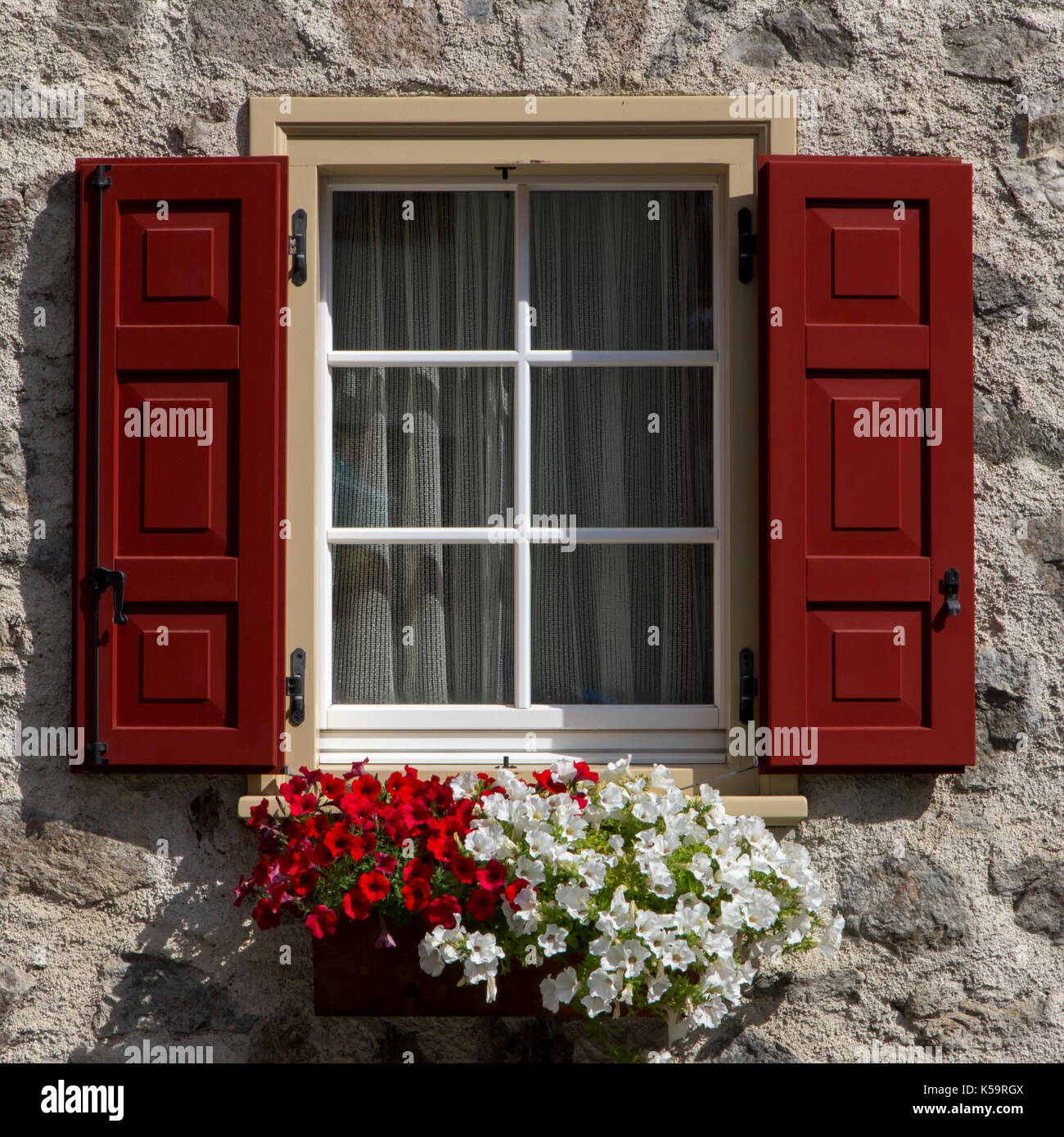 Des fleurs au rebord de fenêtre avec des volets en bois ouverte, Livigno, italie Banque D'Images