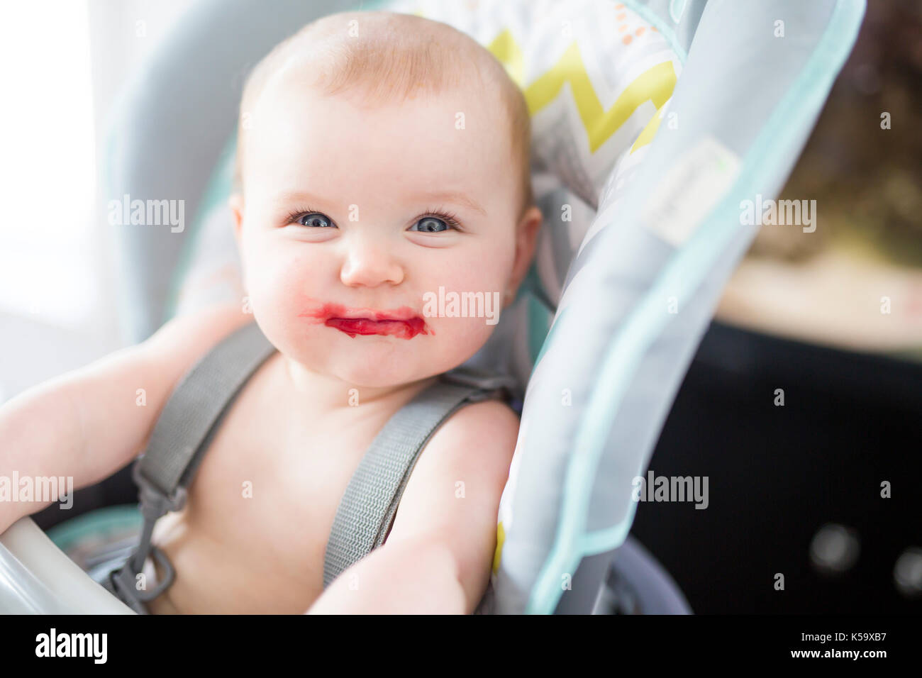 Baby Girl sitting dans une chaise haute pour manger Banque D'Images