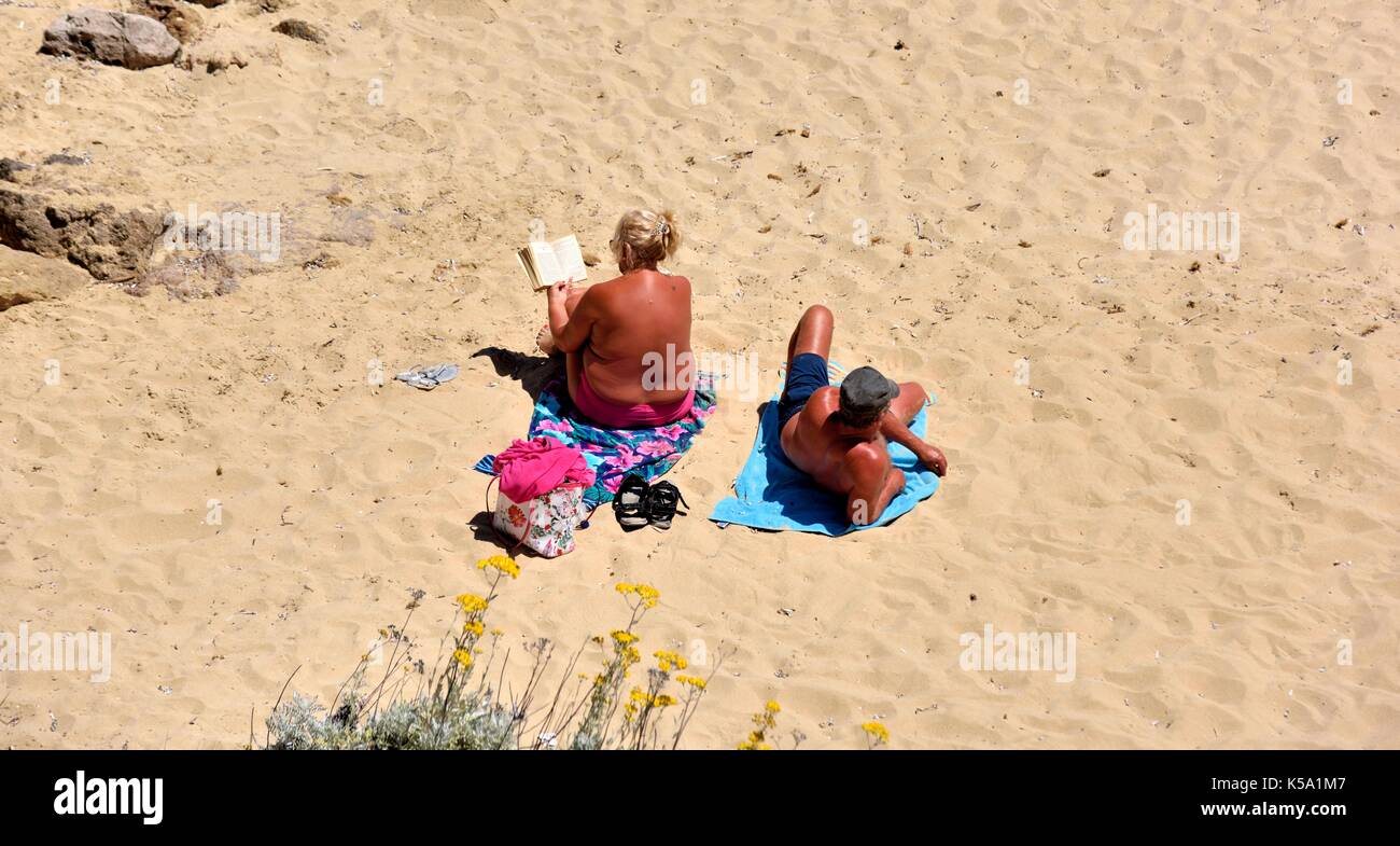 Couple bronzé à bronzer sur une plage Minorque Minorque espagne Banque D'Images