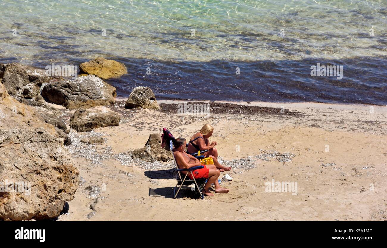 Couple bronzé à bronzer sur une plage Minorque Minorque espagne Banque D'Images