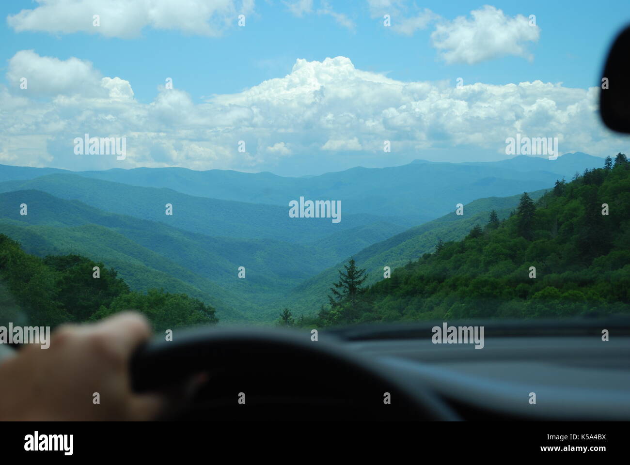 La main des hommes sur volant. large vue à travers la vitre avant de la voiture sur le paysage de montagnes Banque D'Images