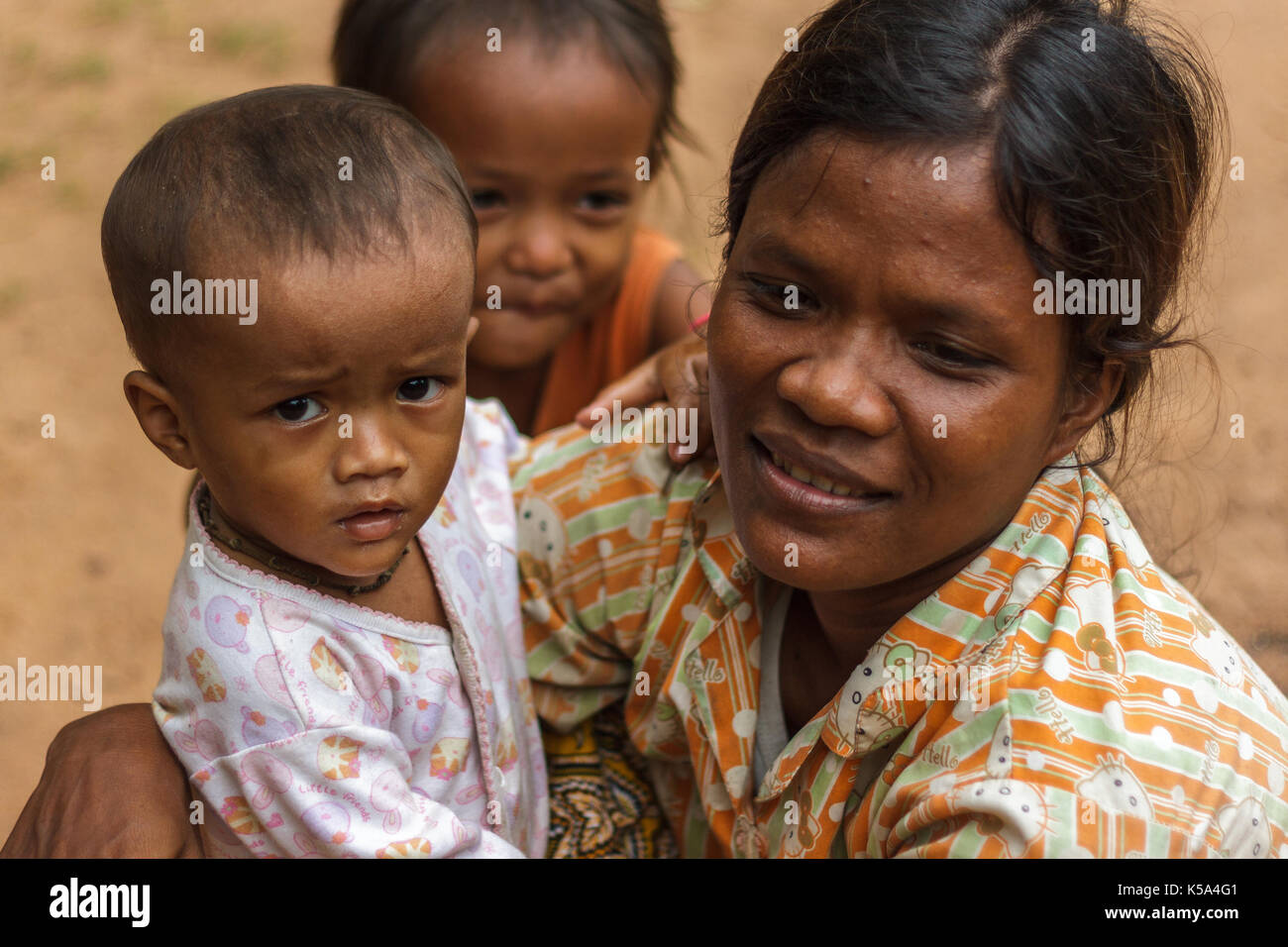 Siem Reap, Cambodge - 9/12/2015 : une mère s'accroupit à côté de ses enfants dans un village. Banque D'Images