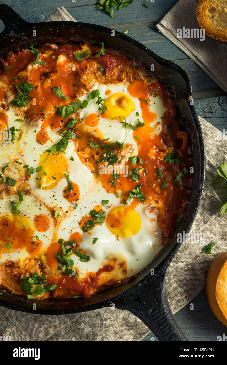 Shakshuka saucy fait maison avec des oeufs coriandre et tomates Banque D'Images