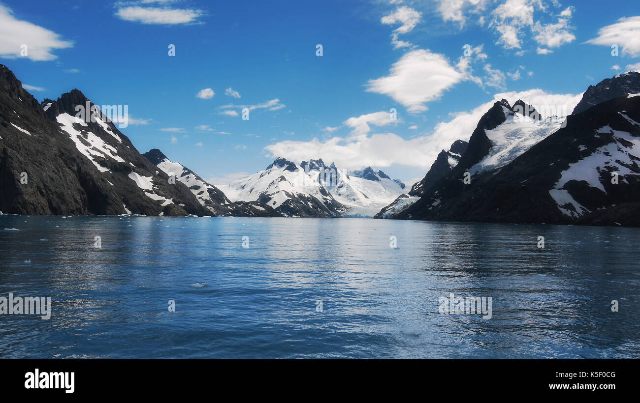 Vue sur les pentes des montagnes enneigées et l'eau calme du fjord drygalski sur l'île de Géorgie du sud, sud de l'océan atlantique. Banque D'Images