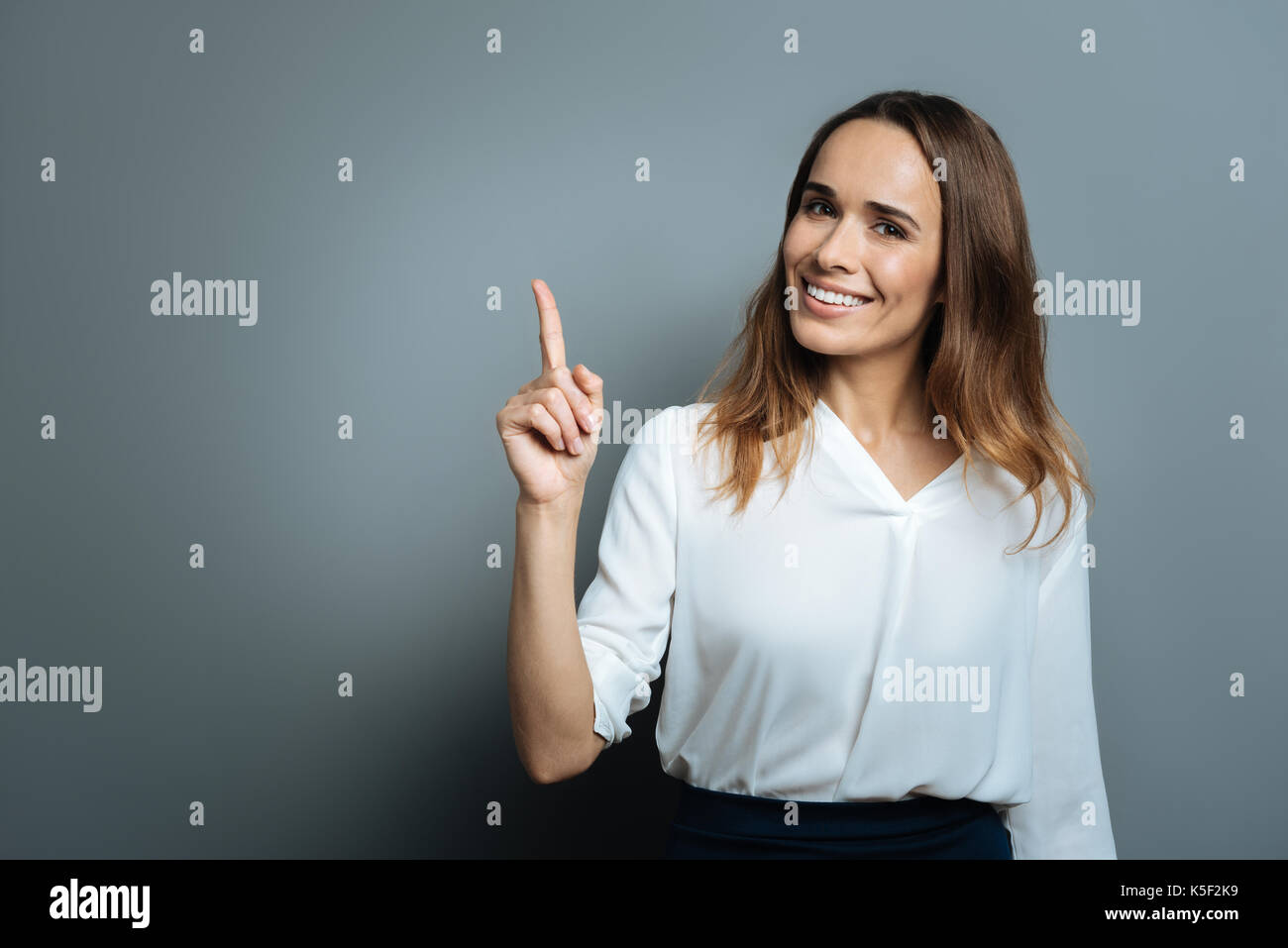 Femme heureuse joyeuse avec son doigt pointé vers le haut Banque D'Images