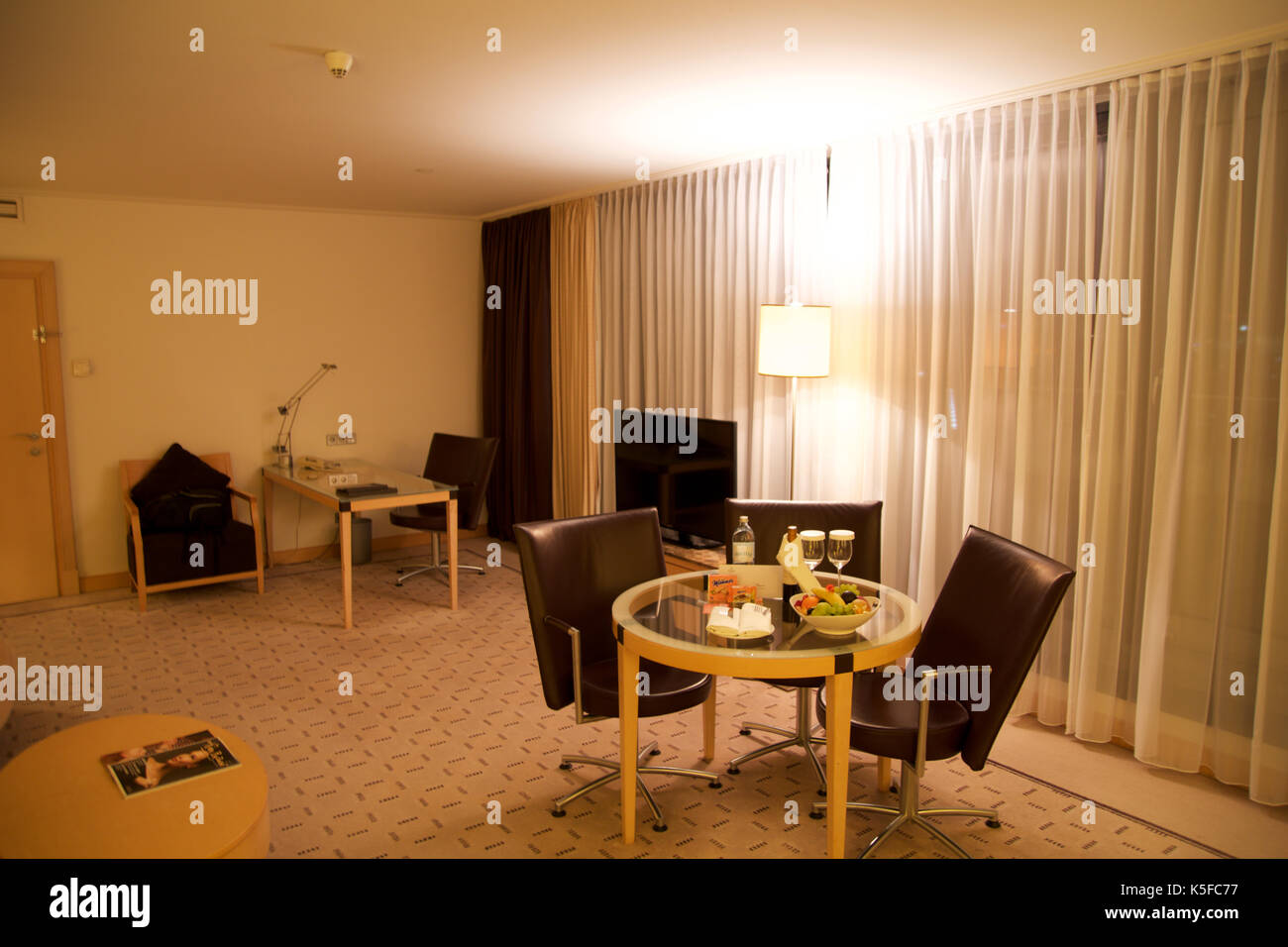 Vienne, Autriche - avril 28th, 2017 : soirée romantique avec bouteille de vin rouge, de sucreries et de fruits dans la chambre d'hôtel de luxe sur une table avec trois chaises en cuir, hilton suite penthouse Banque D'Images