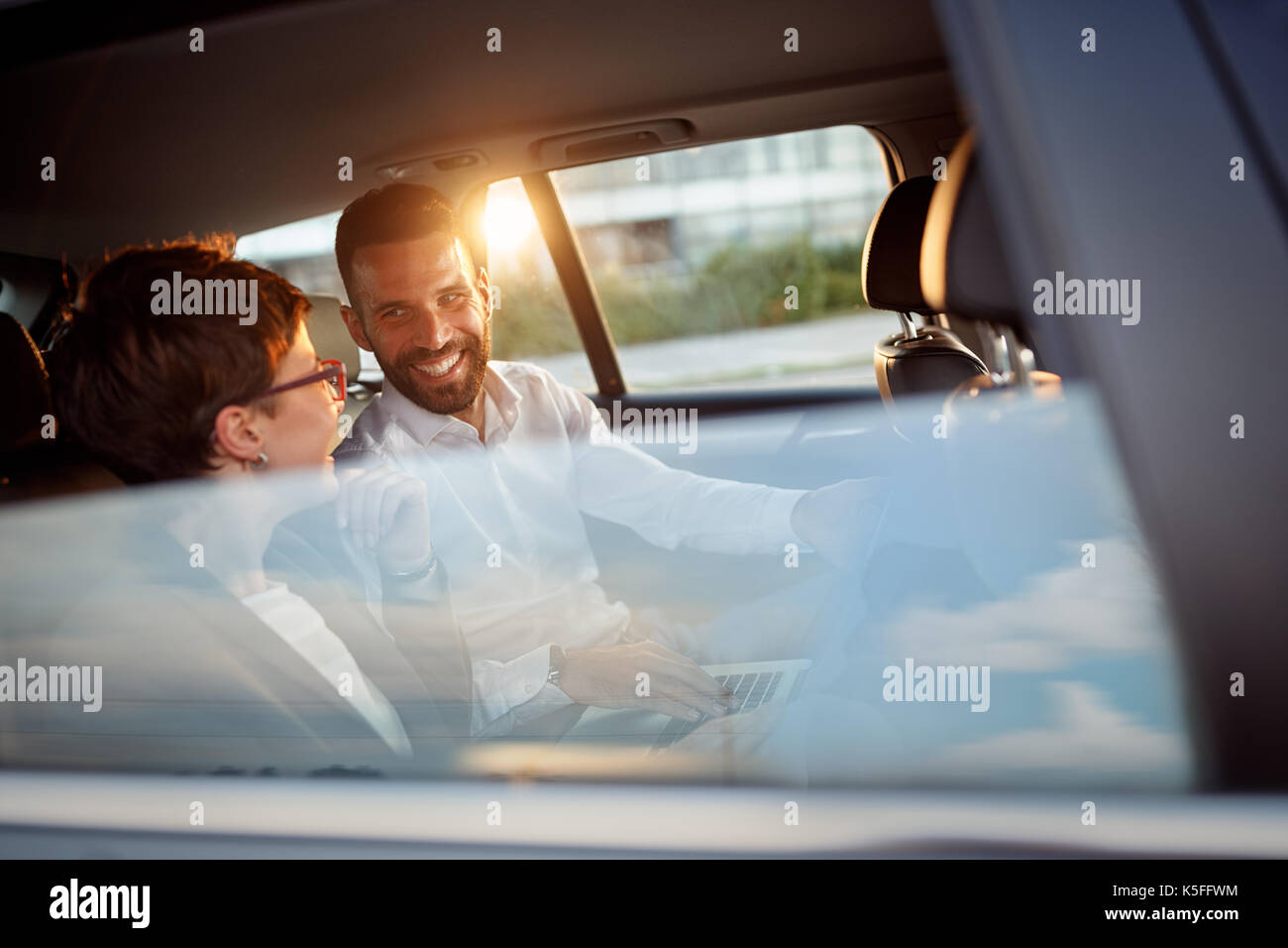 Smiling business people working in backseat of car Banque D'Images