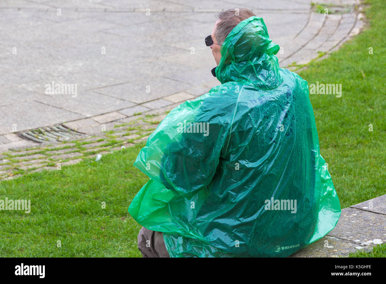 Swanage, Dorset, UK. Sep 9, 2017. Météo France : forte pluie et tonnerre à Swanage. Homme assis sur un mur en poncho imperméable vert. Credit : Carolyn Jenkins/Alamy Live News Banque D'Images