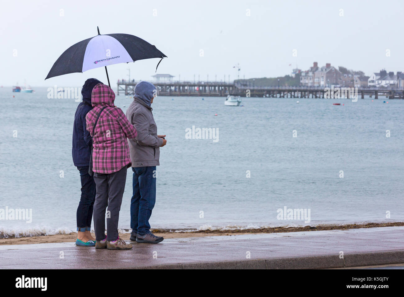Swanage, Dorset, UK. Sep 9, 2017. Météo France : forte pluie et tonnerre à Swanage. Trois personnes à l'abri sous égide essaie de garder au sec avec Pier Swanage dans la distance. Credit : Carolyn Jenkins/Alamy Live News Banque D'Images
