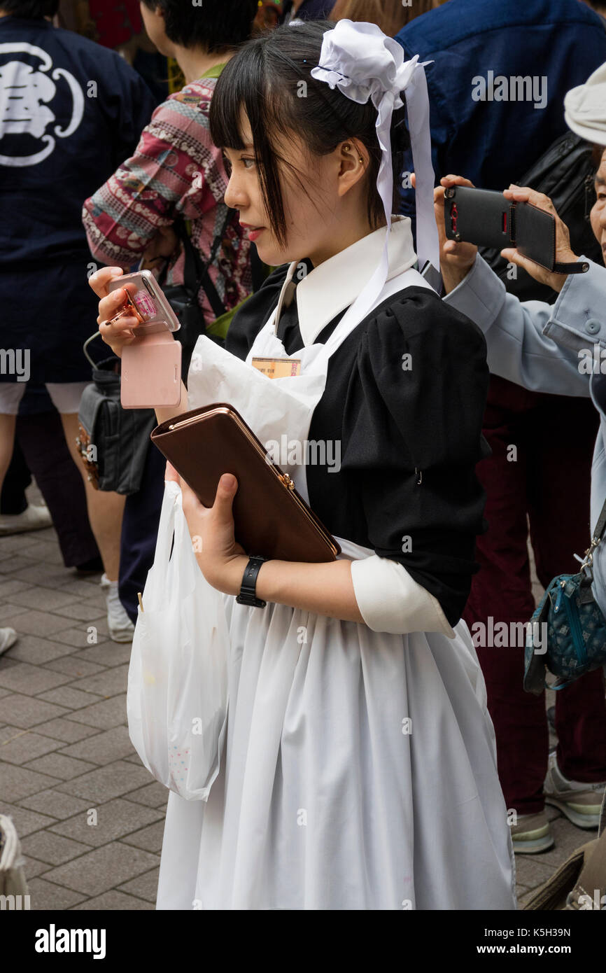 Tokyo, Japon - 14 mai 2017 : cosplay anime girl comme employée de maison dans la rue avec son téléphone portable Banque D'Images