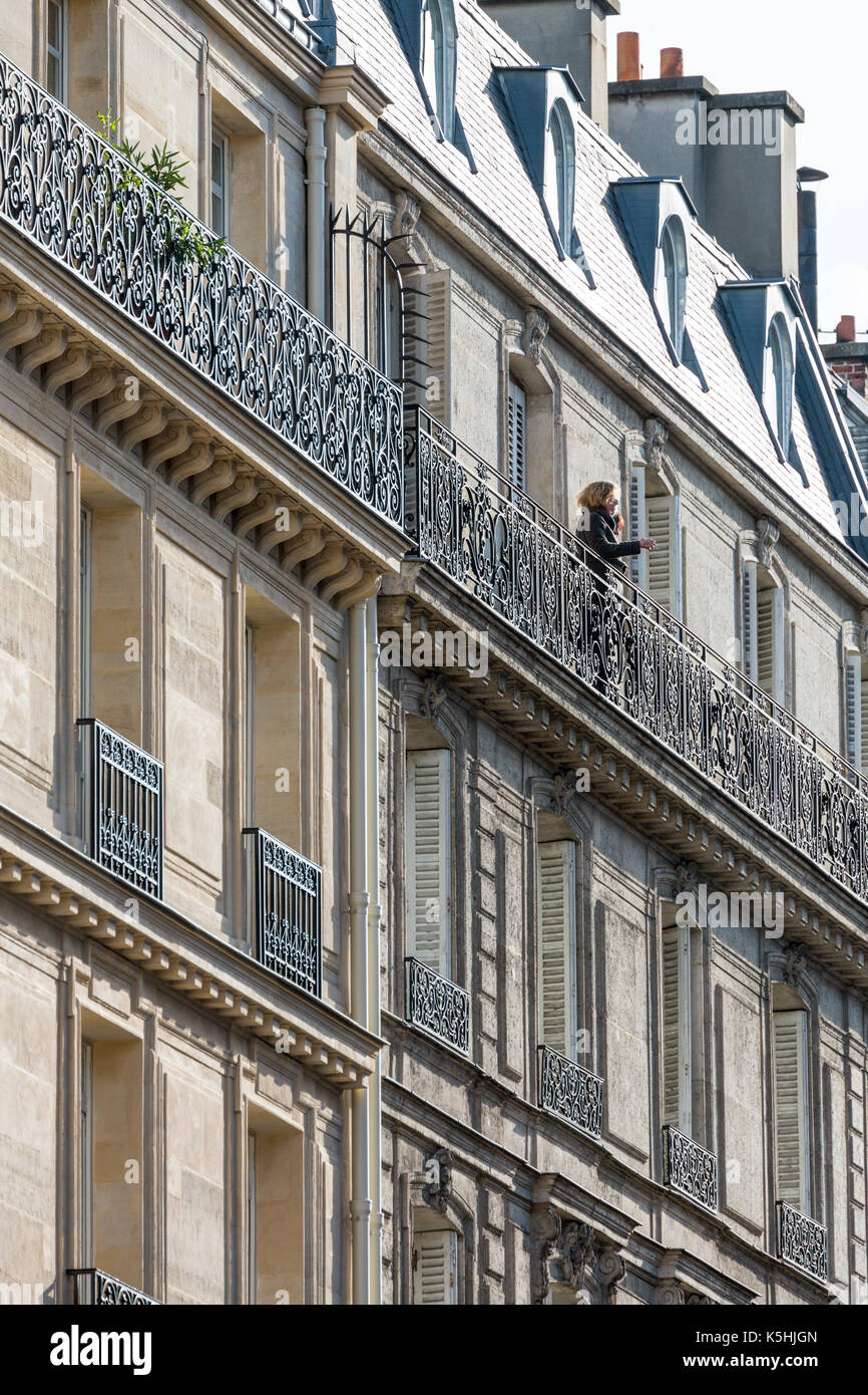 Femme qui fume sur le balcon de l'immeuble typique de Paris, France Banque D'Images