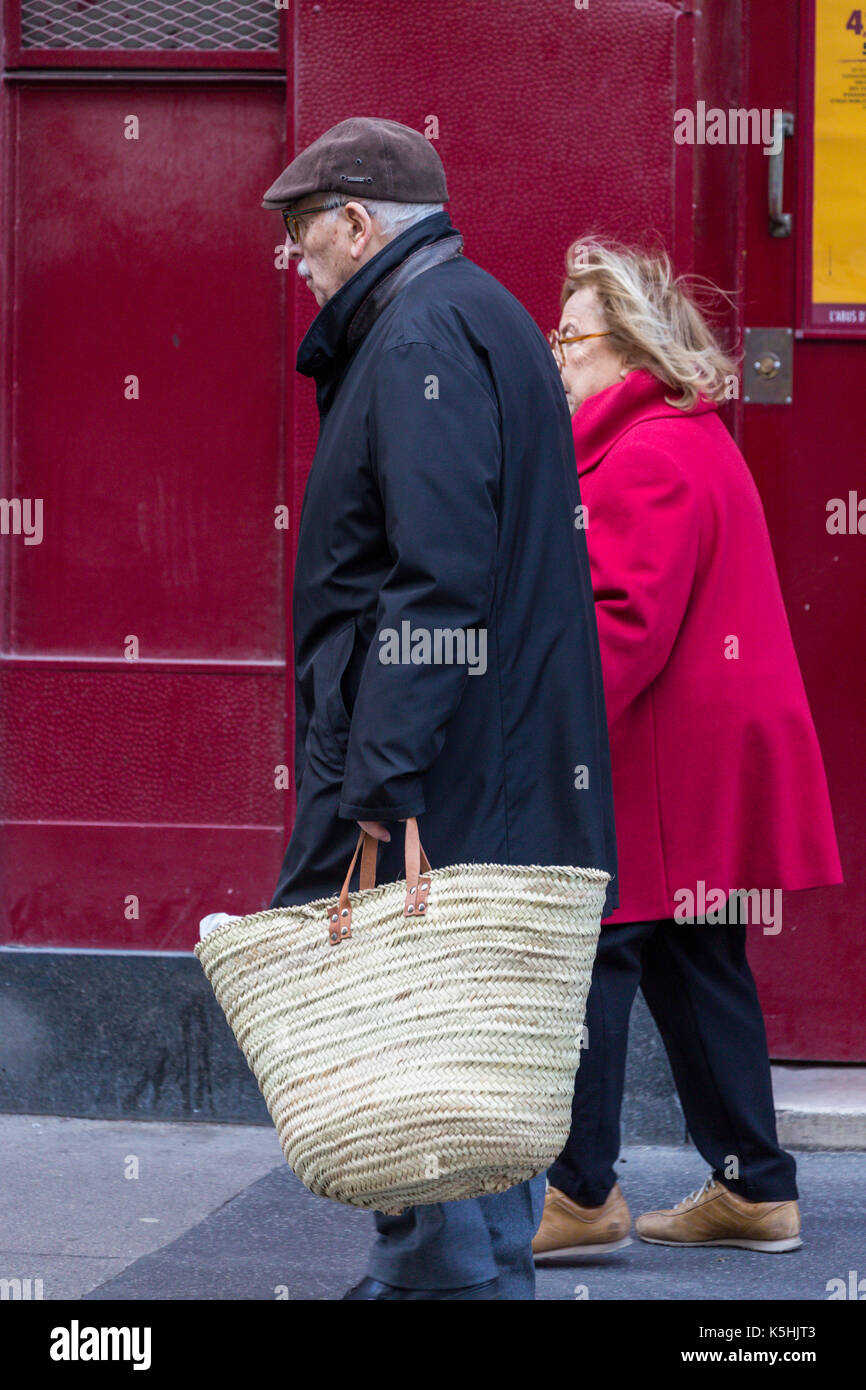 Vieux couple marche main dans la main dans la rue, l'homme avec un grand sac de shopping, 7ème arrondissement, Paris, France Banque D'Images