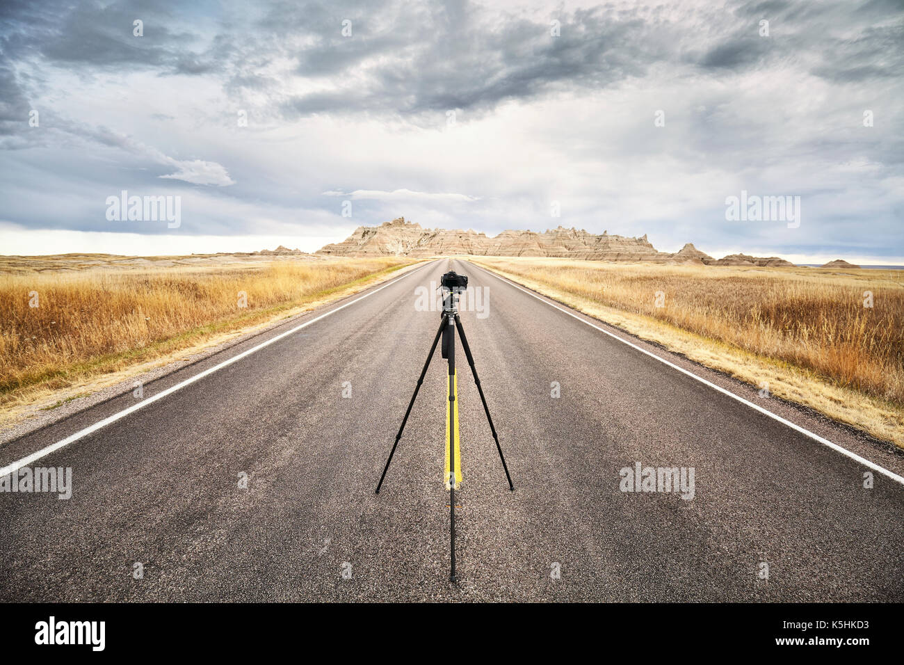 Appareil photo sur trépied photo professionnel sur une route vide au coucher du soleil, l'accent sur l'appareil photo de voyage ou de travail, concept, Badlands National Park, South Dakota, USA Banque D'Images