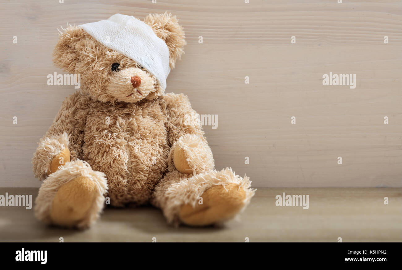 L'enfant est malade concept.ours avec bandage assis sur un sol en bois Banque D'Images
