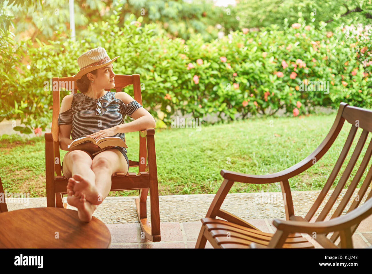 Femme avec livre d'oeil sur le côté assis sur fond d'été ensoleillé Banque D'Images