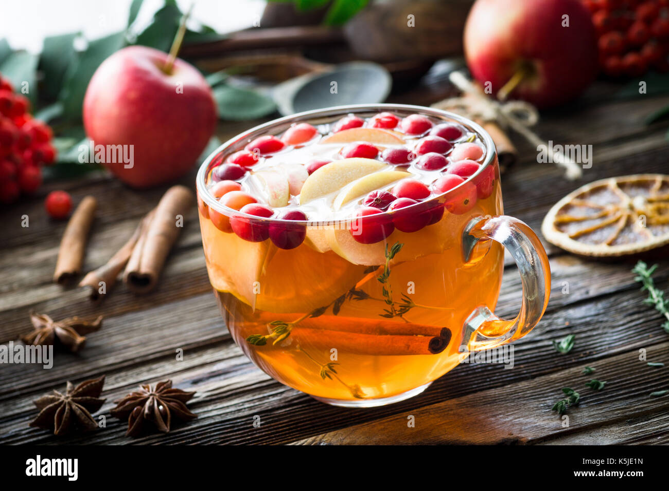 Plateau de fruits d'hiver et aux canneberges, pommes, cannelle, citron, miel et thym dans une tasse en verre sur la table en bois. Vue rapprochée, horizontale Banque D'Images