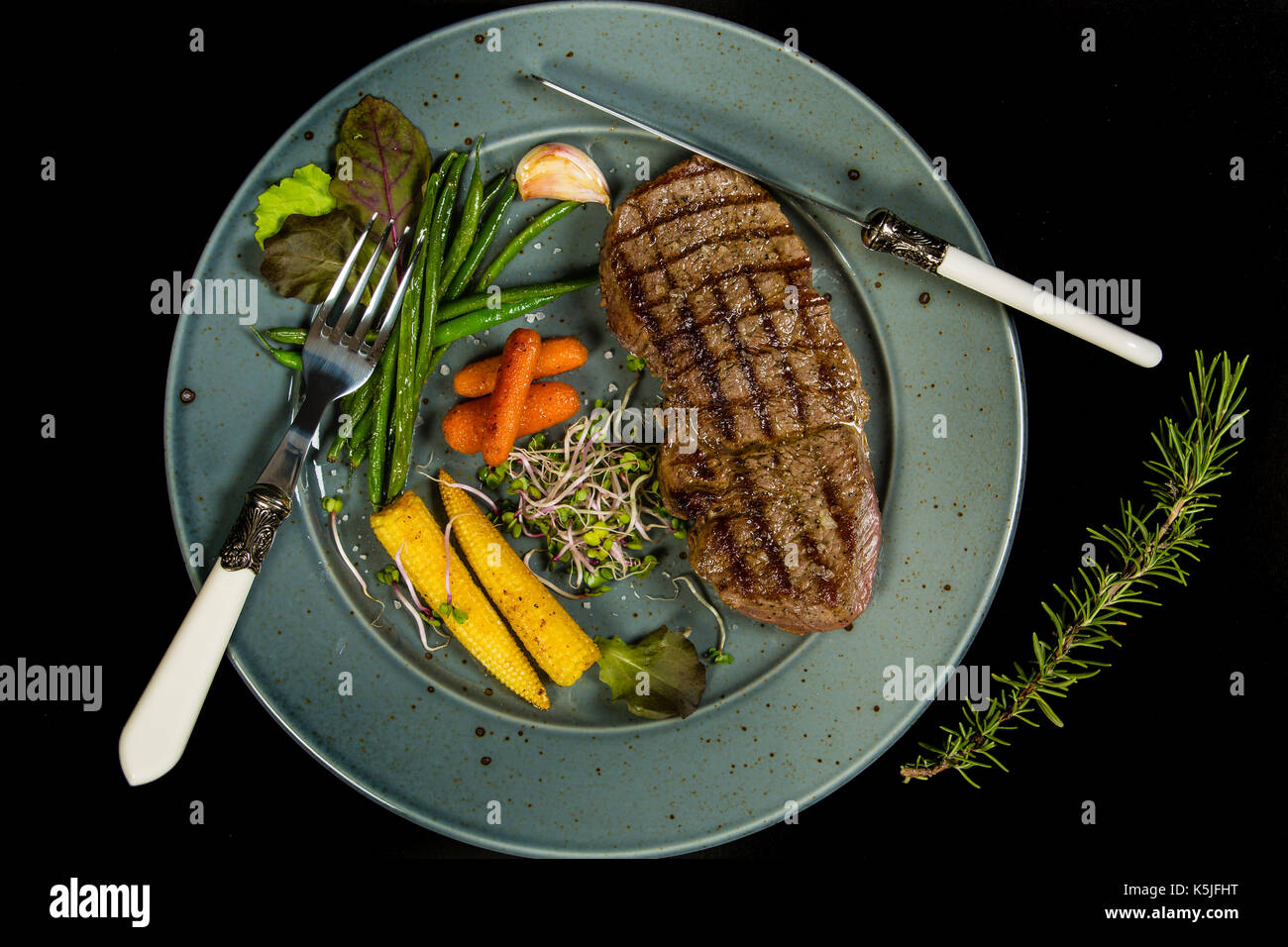 Pavé de boeuf grillé avec légumes glacés sur le fond noir Banque D'Images