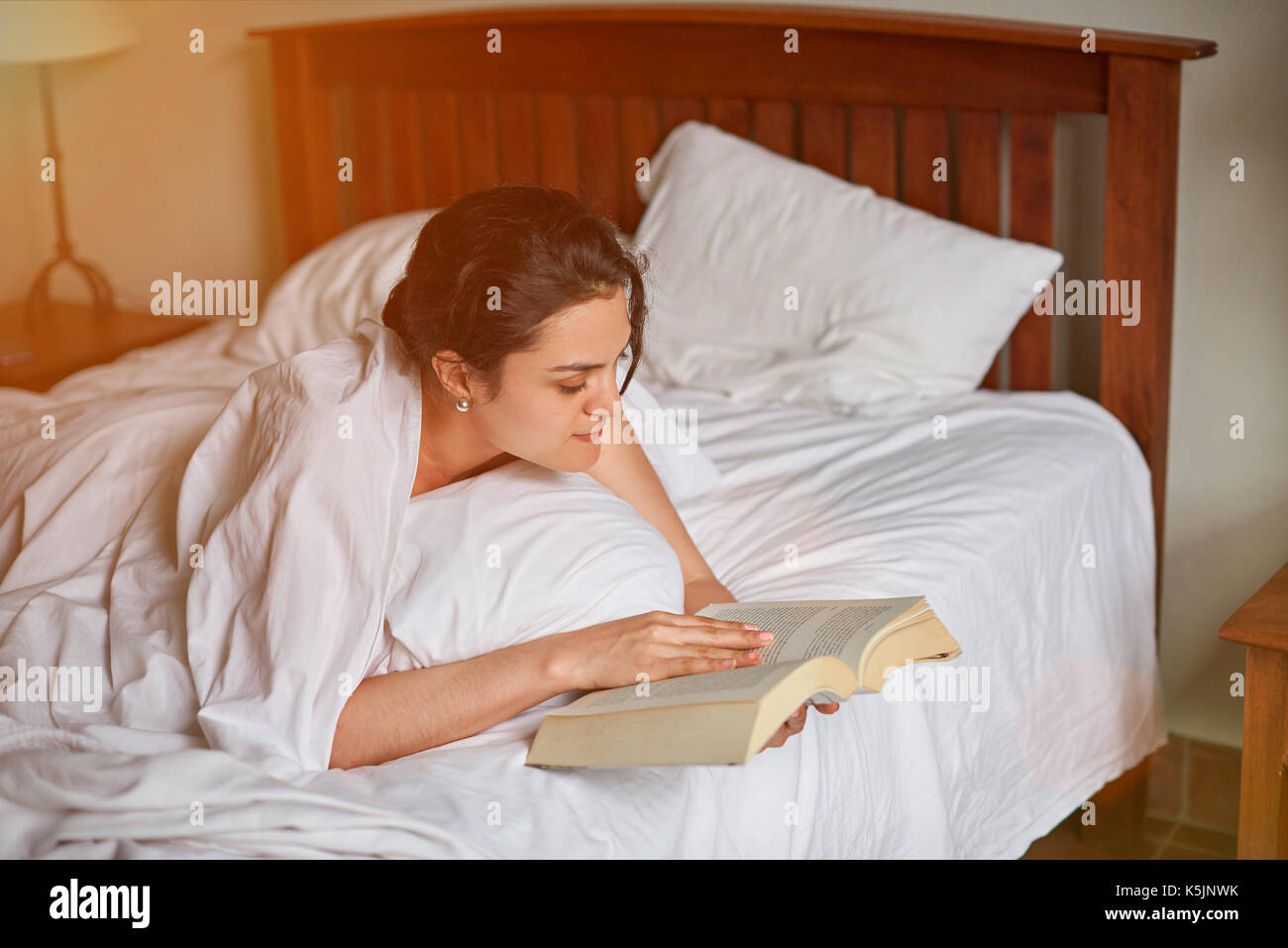 Reading book in bed thème. Jeune femme lisez le livre dans la chambre Banque D'Images