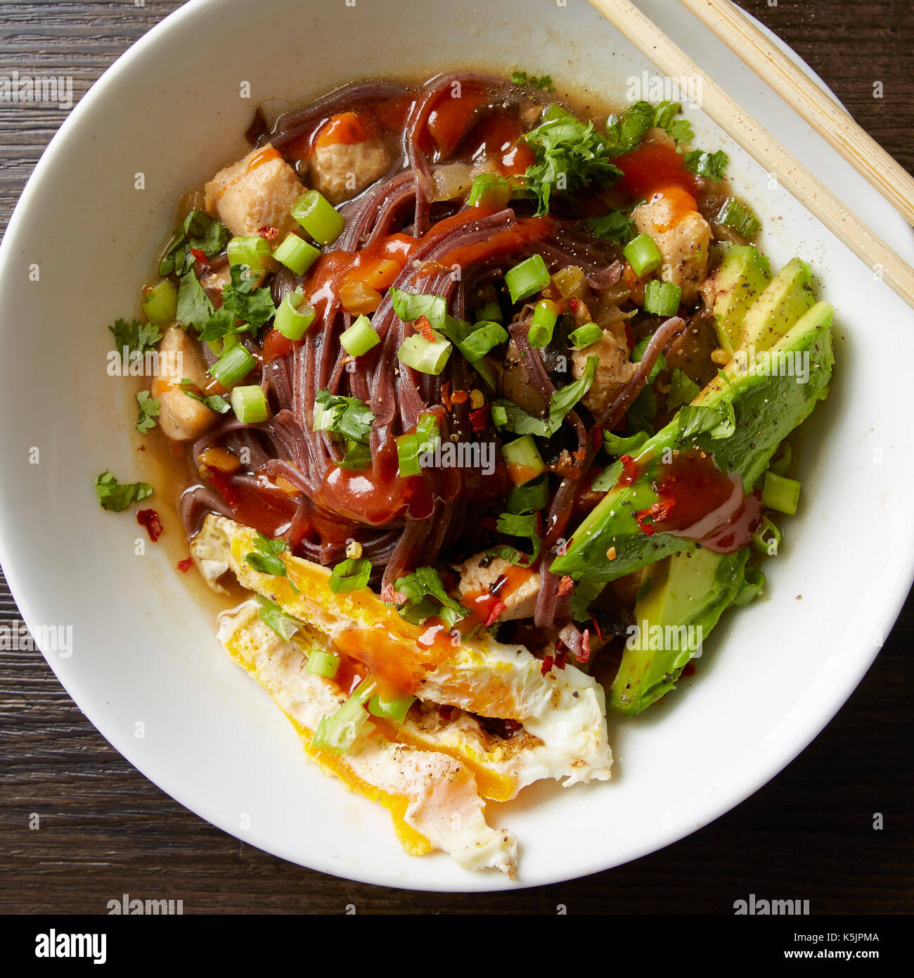 Bol blanc de poulet aux légumes et aux oeufs pho, avocat et sriracha Banque D'Images