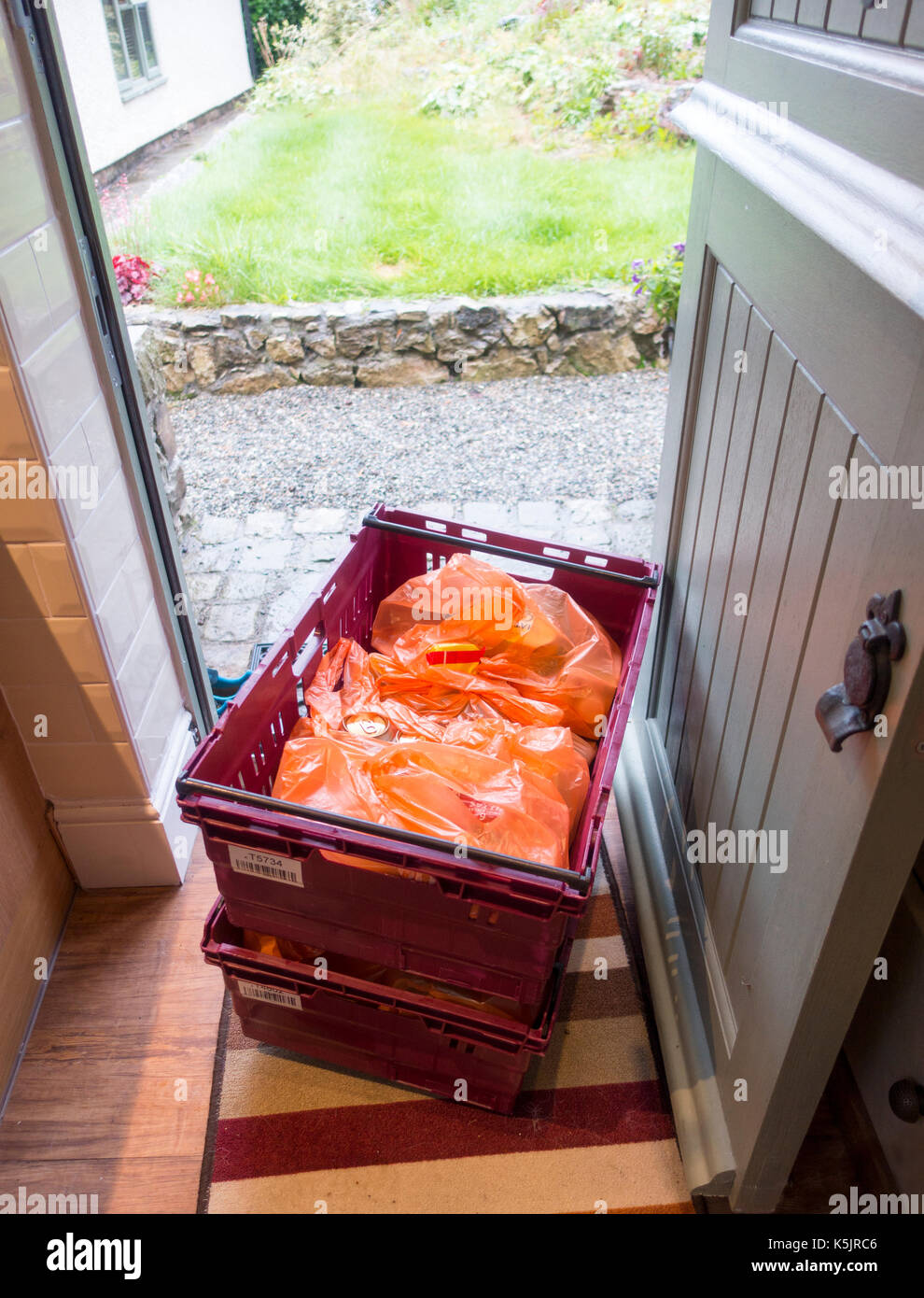 Livraison à domicile de denrées alimentaires provenant de la chaîne de livraison à domicile supermarché Sainsburys sur seuil de porte où il en caisses de livraison à une adresse à la maison, au Pays de Galles Banque D'Images