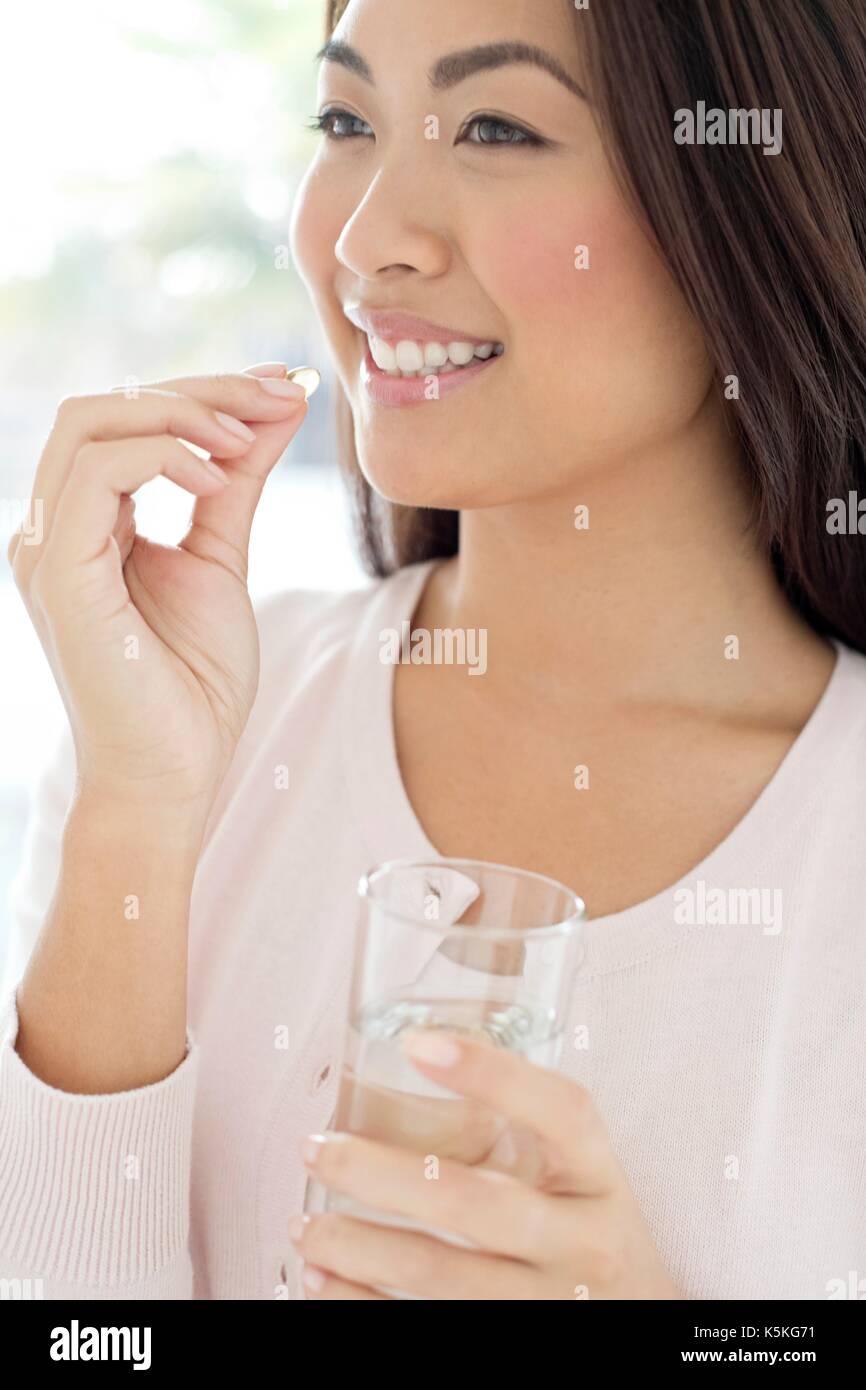 Jeune femme tenant comp et verre d'eau. Banque D'Images
