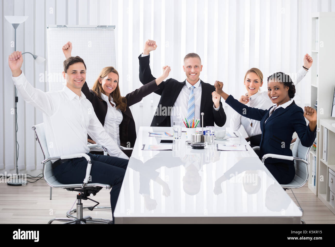 Group of smiling multi ethnic woman raising arms in office Banque D'Images