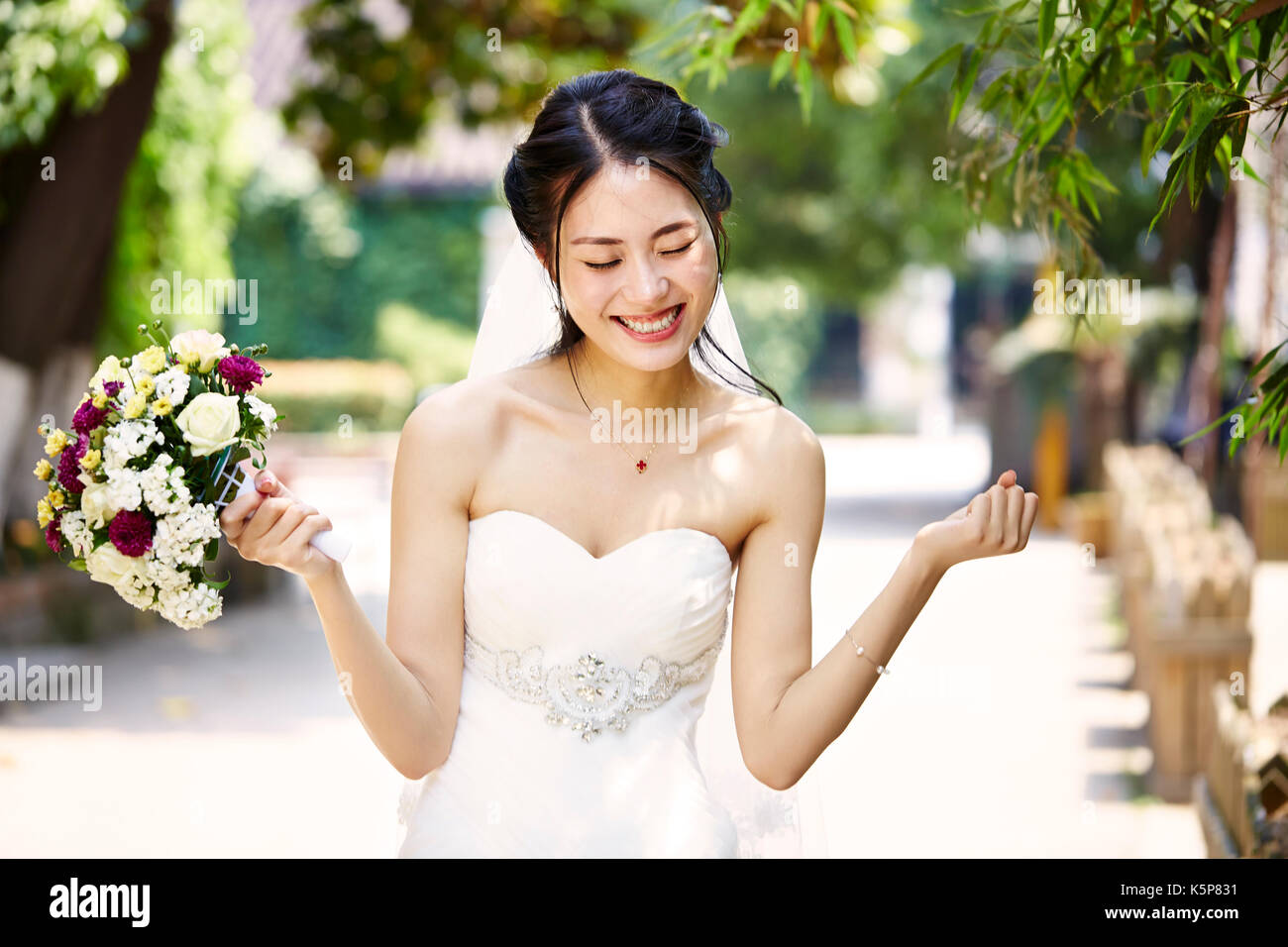 Jeune et belle Asian bride se réjouir avec bouquet à la main. Banque D'Images