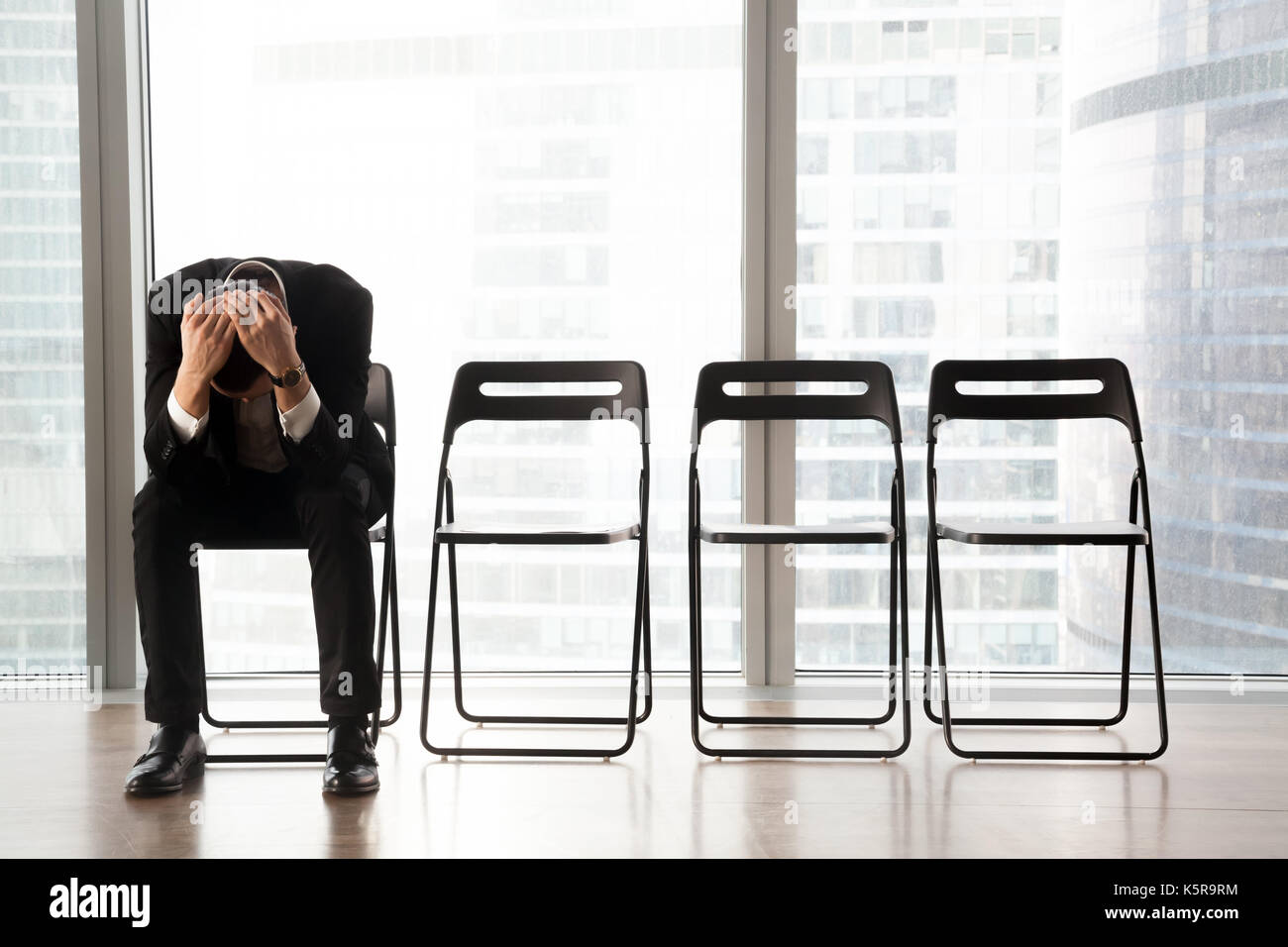 Souligné upset businessman sitting on chair, reçu de mauvaises nouvelles. Banque D'Images