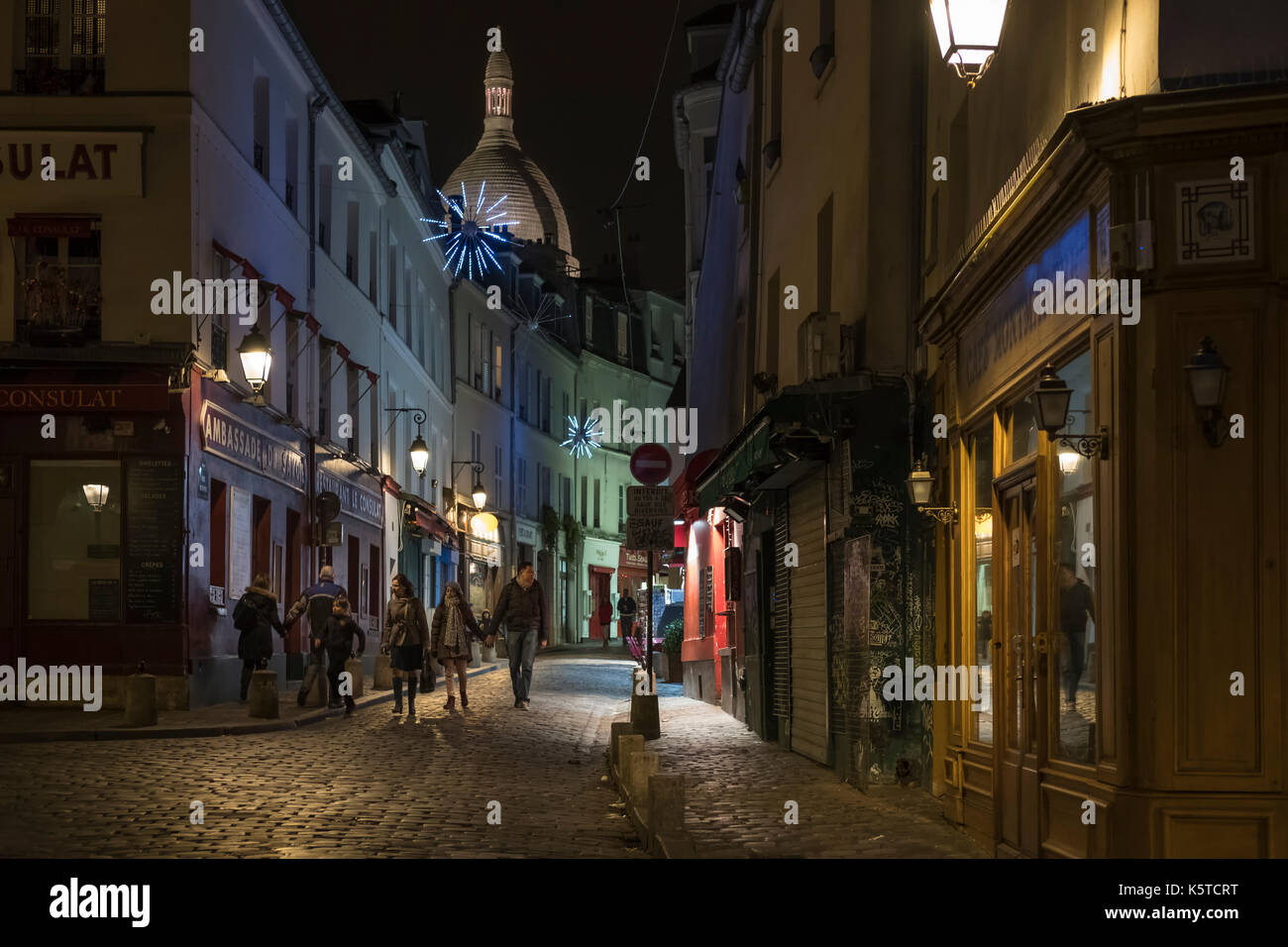 Les touristes à pied dans une petite rue pittoresque de Montmartre à Paris le soir de Noël avec de belles lumières. Banque D'Images