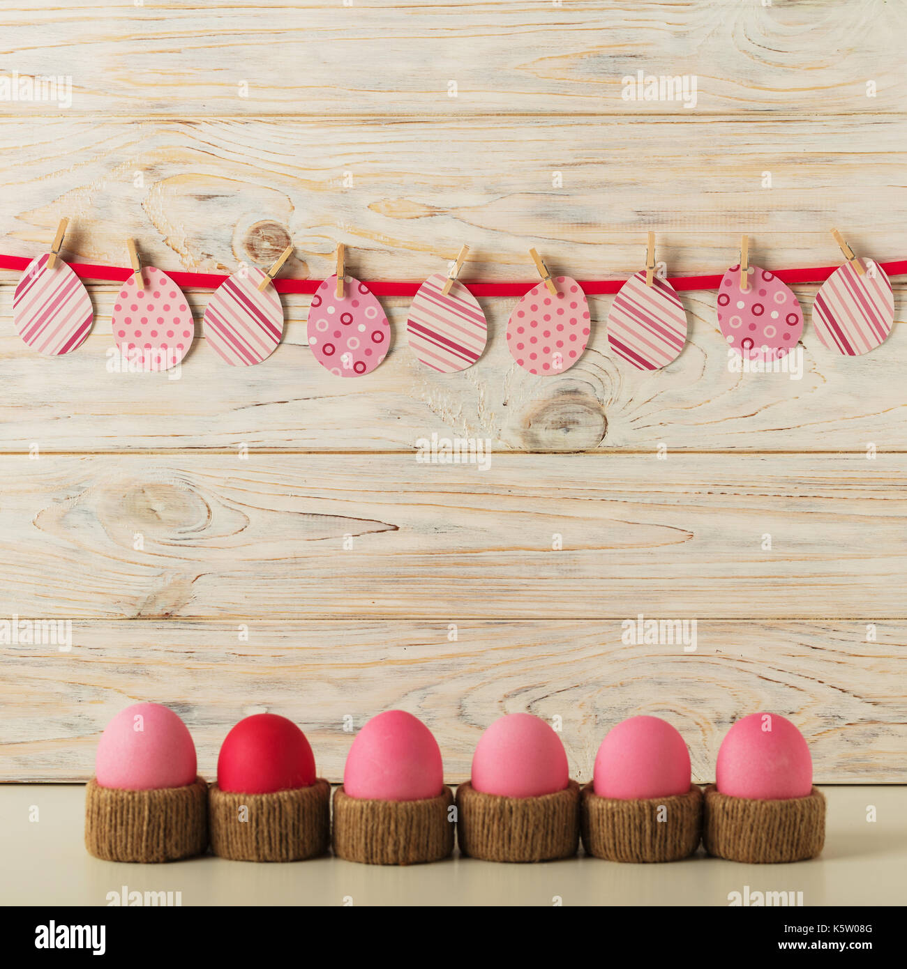 Décoration de Pâques oeufs de Pâques et les oeufs en papier, avec un ruban rose sur un fond en bois clair. Focus sélectif. Banque D'Images