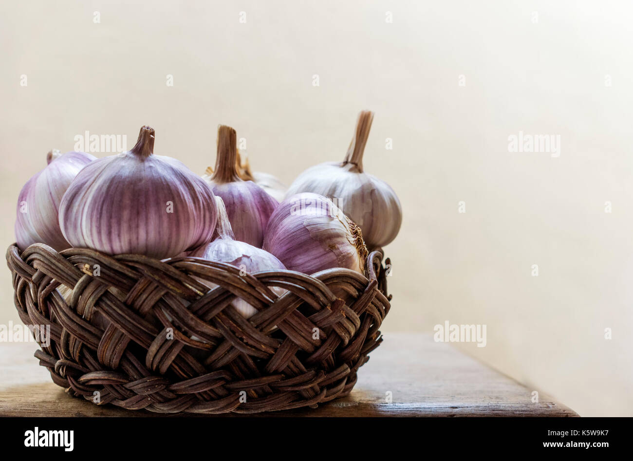 Panier plein de vigne ensemble l'ail violet, sur le dessus d'une table en bois, fond clair, avec copie espace Banque D'Images