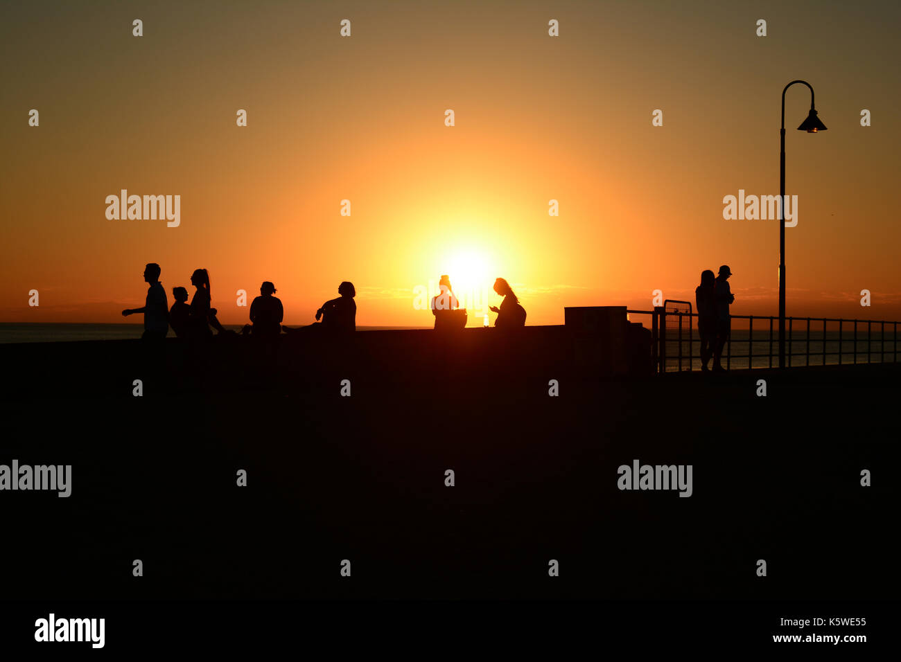 Un superbe coucher de soleil sur la plage en Australie avec des silhouettes de personnes. Banque D'Images