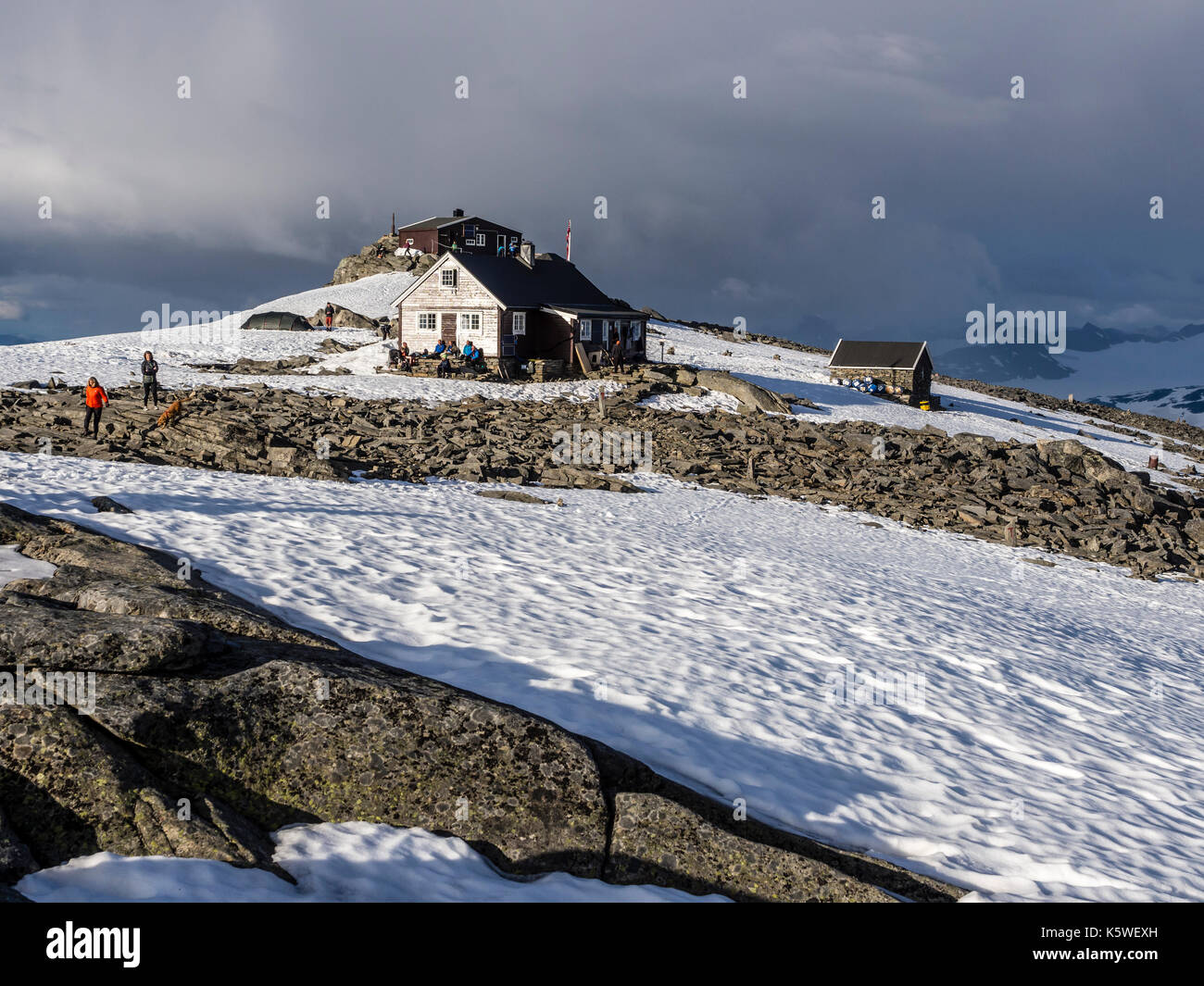 Refuge de montagne sur Fannaråken au sommet de la montagne, les randonneurs s'asseoir à l'extérieur de la cabane, profiter du soleil, le parc national de Jotunheimen, Norvège Banque D'Images