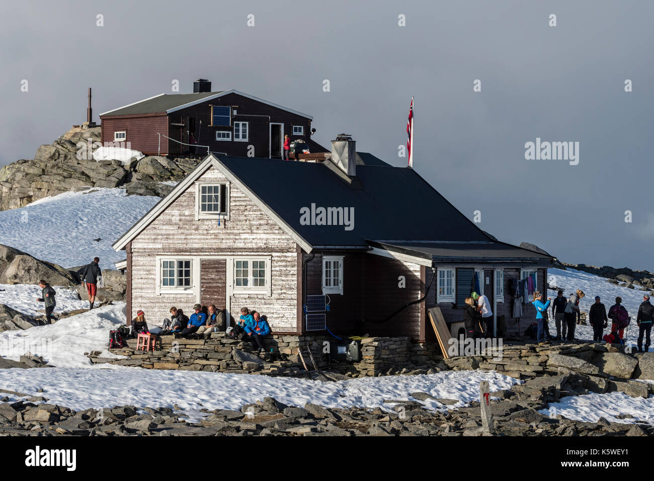 Refuge de montagne sur Fannaråken au sommet de la montagne, les randonneurs s'asseoir à l'extérieur de la cabane, profiter du soleil, le parc national de Jotunheimen, Norvège Banque D'Images