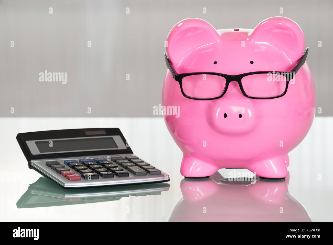 Close-up of a tirelire avec lunettes et Calculatrice Banque D'Images