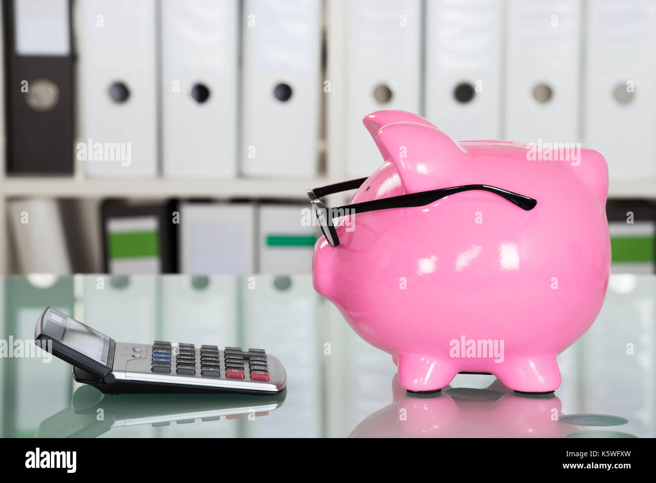 Close-up of Piggybank portant des lunettes et une calculatrice sur 24 Banque D'Images