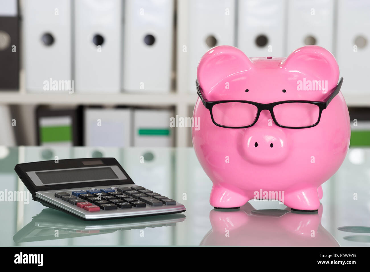 Close-up of Piggybank portant des lunettes et une calculatrice sur 24 Banque D'Images