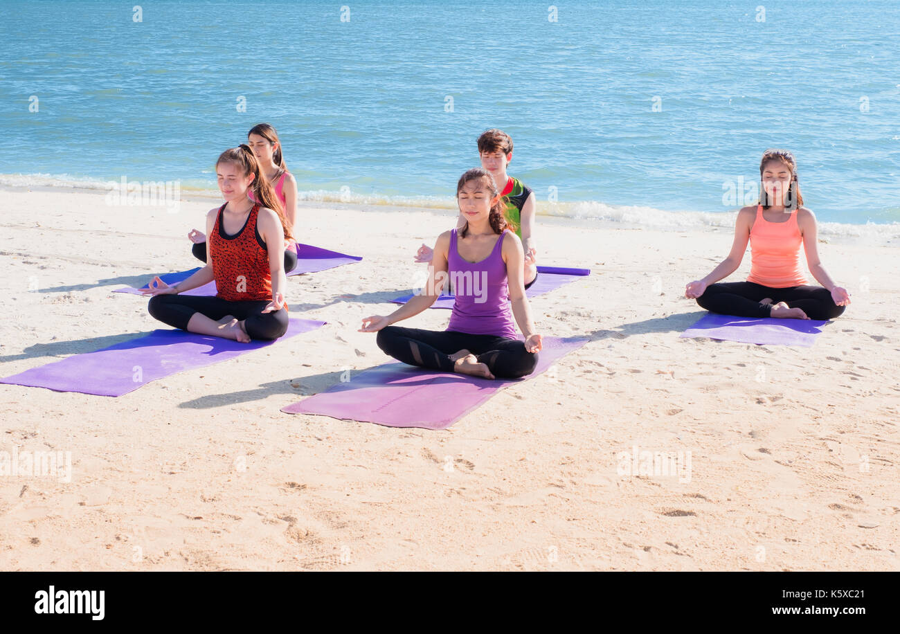 Cours de yoga en mer plage de sunny day ,groupe de personnes faisant lotus posent avec clam vous détendre émotion,la méditation,pose le bien-être et mode de vie sain et équilibré. Banque D'Images