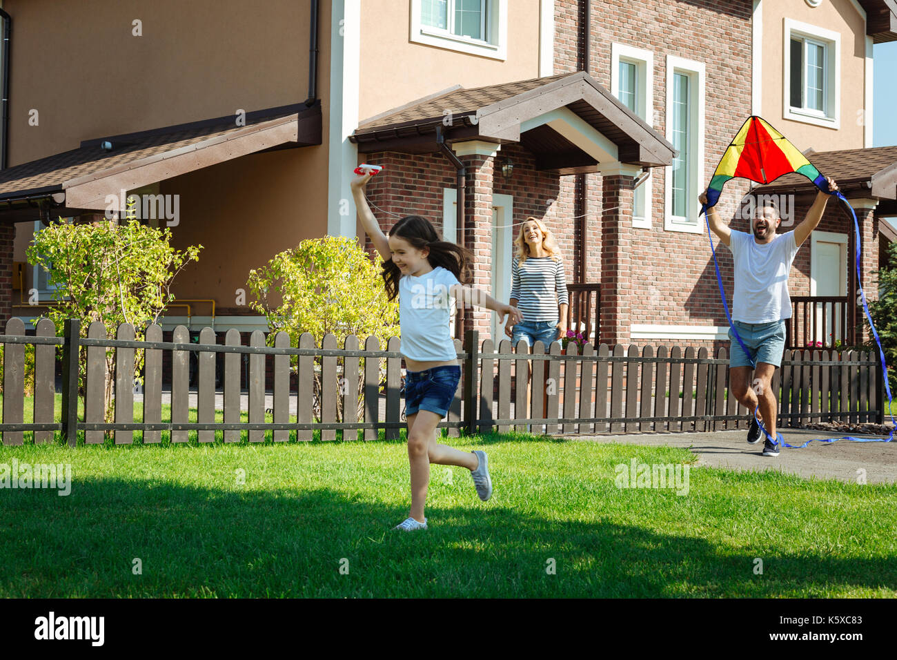 Cute girl le lancement d'un cerf-volant avec son père dans une cour Banque D'Images