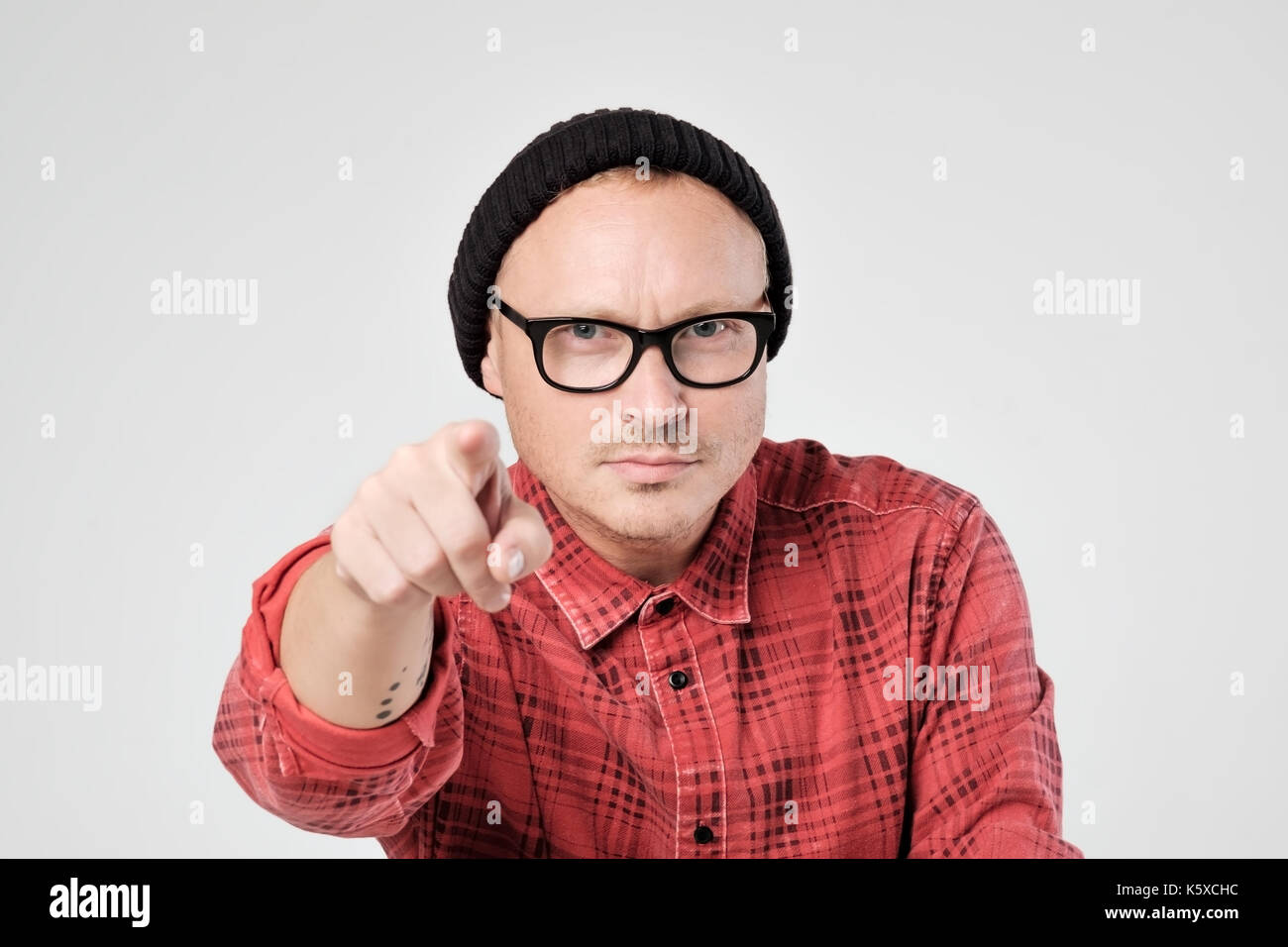 Un jeune homme en chapeau noir et verres comme hipster regarde la caméra en déplaisir. Il strechs part à venir. Banque D'Images