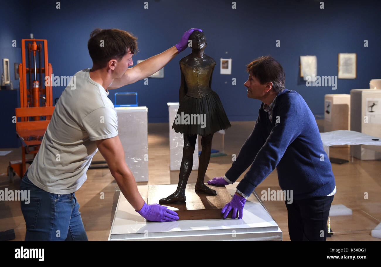 La sculpture en bronze « Little Dancer aged 14ans » d'Edgar Degas est mise en place par Tim Matthews (à gauche) et Nik Zolman (à droite) faisant partie d'une nouvelle exposition, « Degas: A passion for Perfection », au Fitzwilliam Museum de Cambridge. Banque D'Images